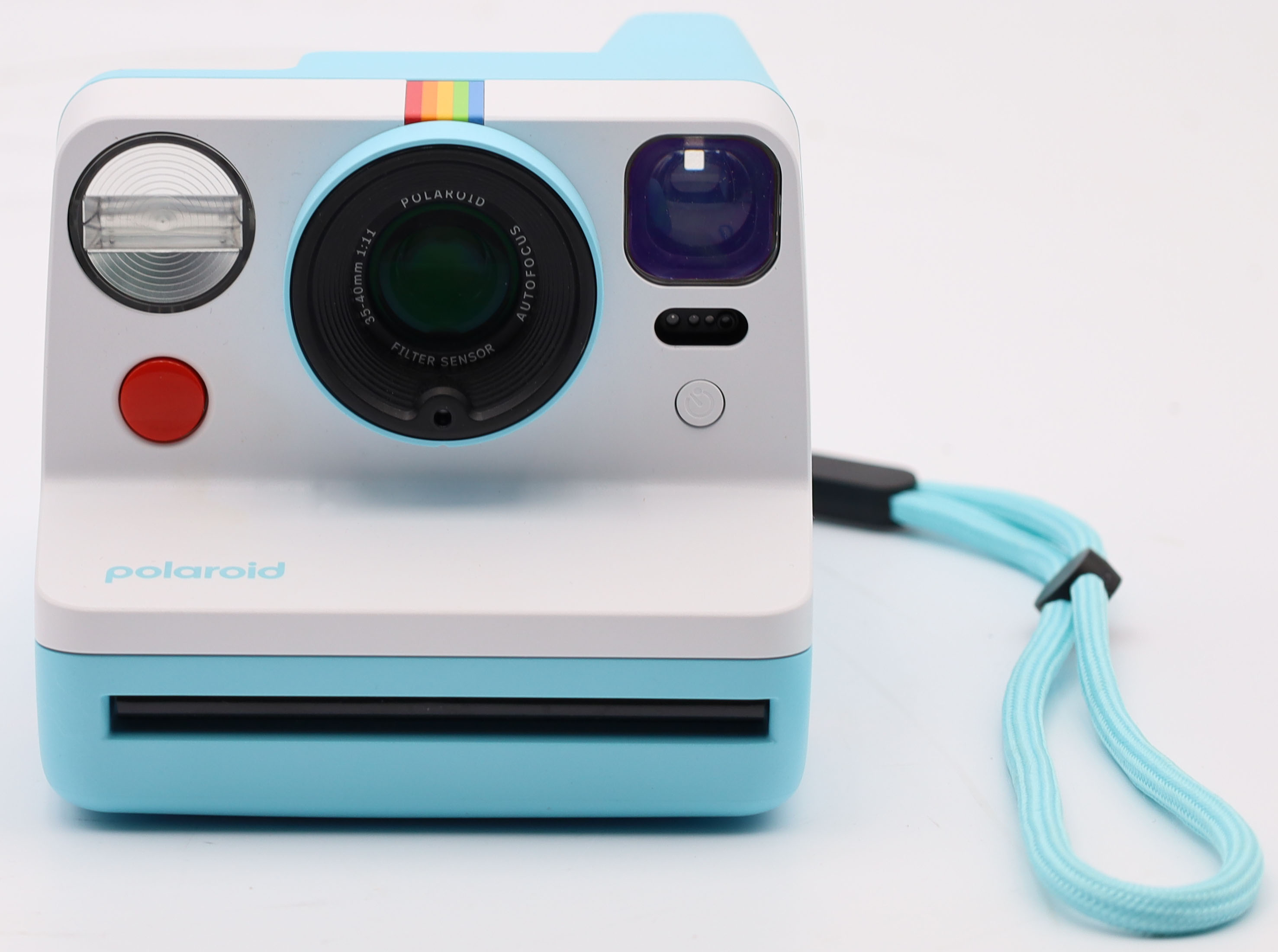 Eine hellblaue Polaroid-Kamera mit weißem Gehäuse und Regenbogen-Akzent.