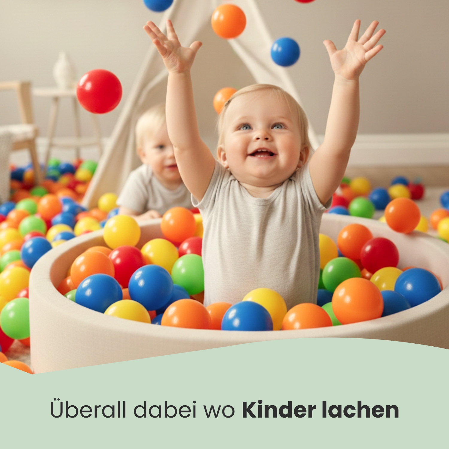 Zwei Babys spielen in einem Bällebad mit bunten Bällen.