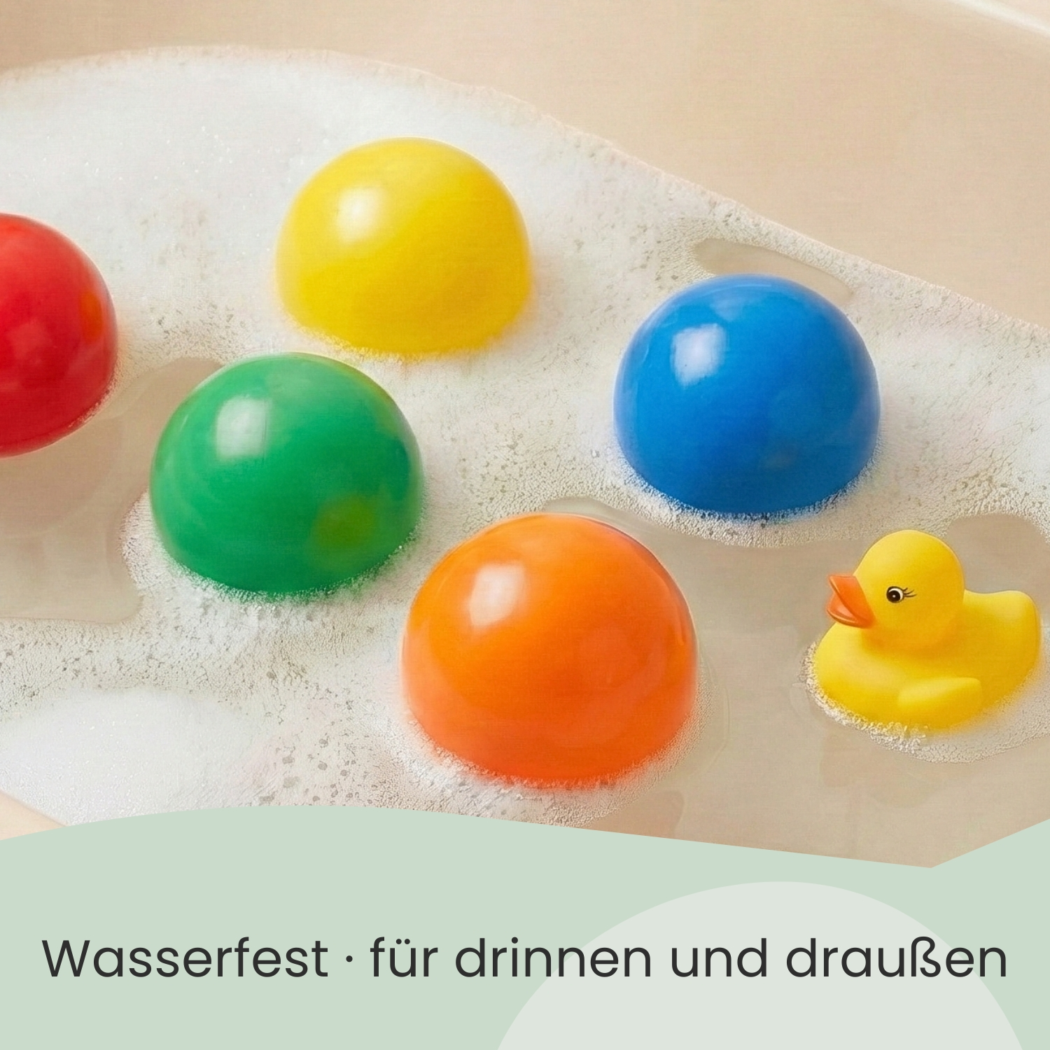 Bunte Bälle und eine gelbe Quietscheente in schaumigem Wasser.