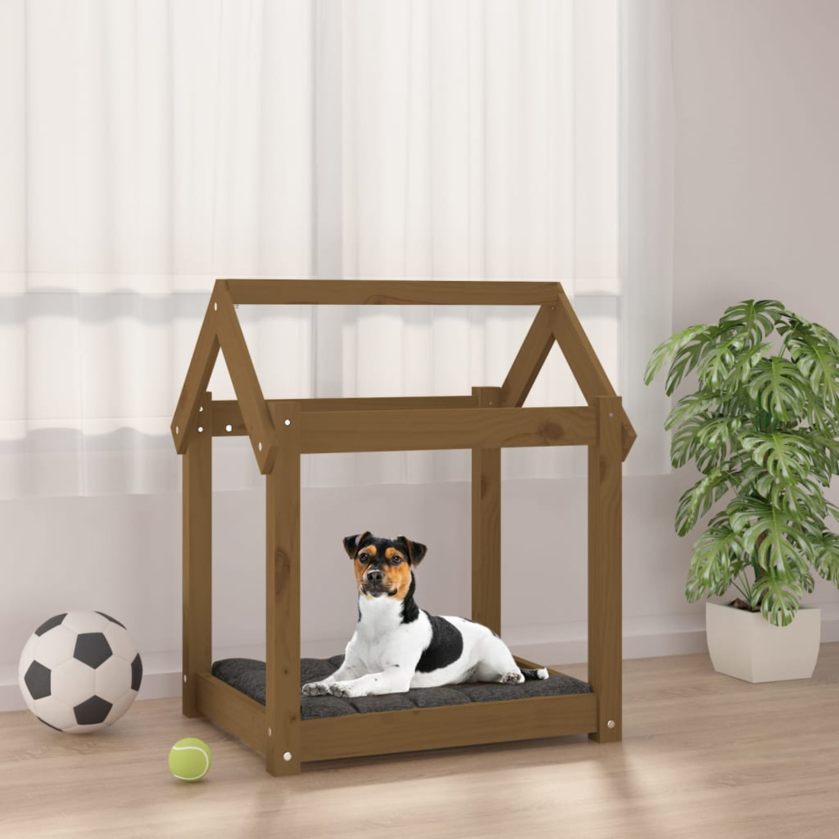 Ein Hund liegt in einem braunen Holzhundhaus mit einem Fußball und einem Ball daneben.