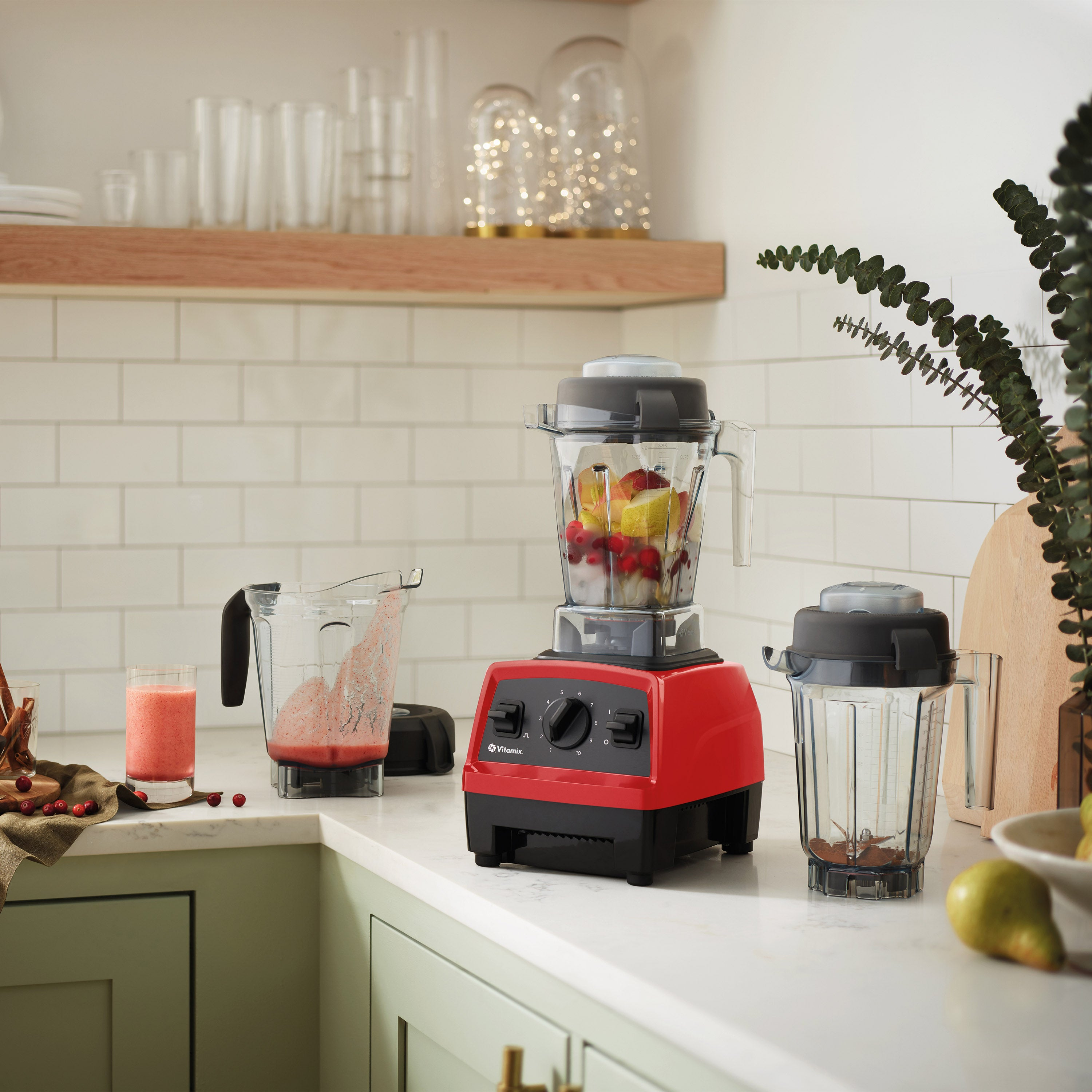 Ein roter Mixer steht auf einer Arbeitsplatte mit Fruchtbechern und einem Glas Saft.