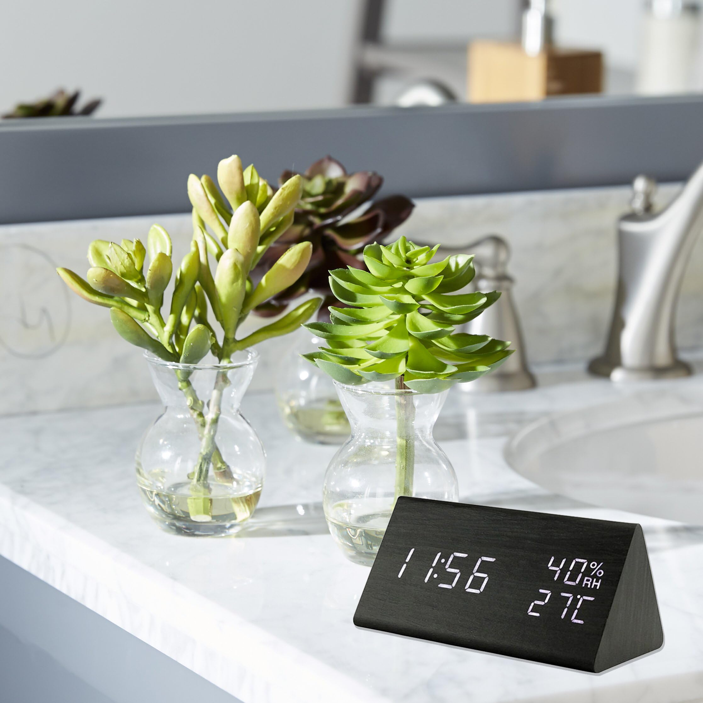 Digitaluhr zeigt 11:56, 40% Luftfeuchtigkeit und 27C auf einem Marmorwaschtisch.