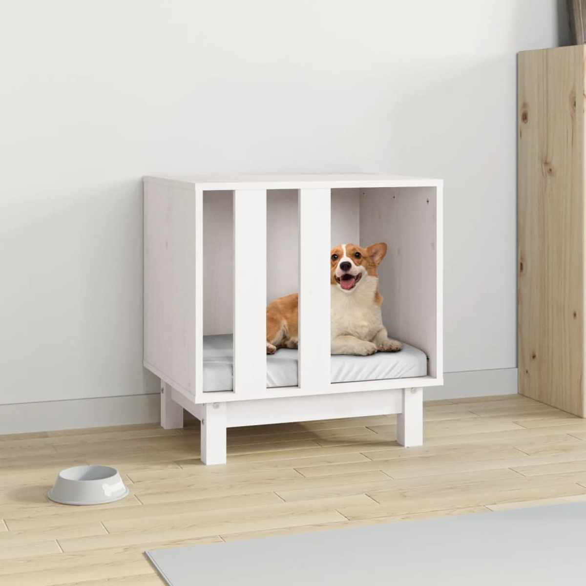 Ein corgi-Hund liegt in einer weißen Hundebox mit einer grauen Matte. Ein Napf steht daneben.