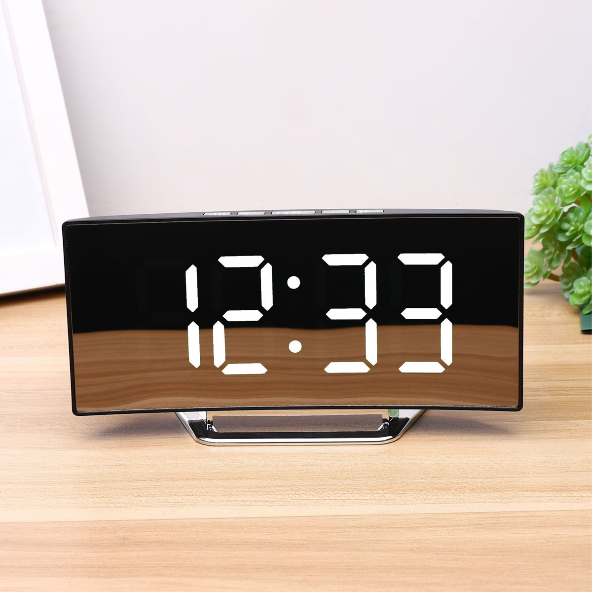 Ein digitaler Wecker zeigt 12:33 auf einem Holztisch.
