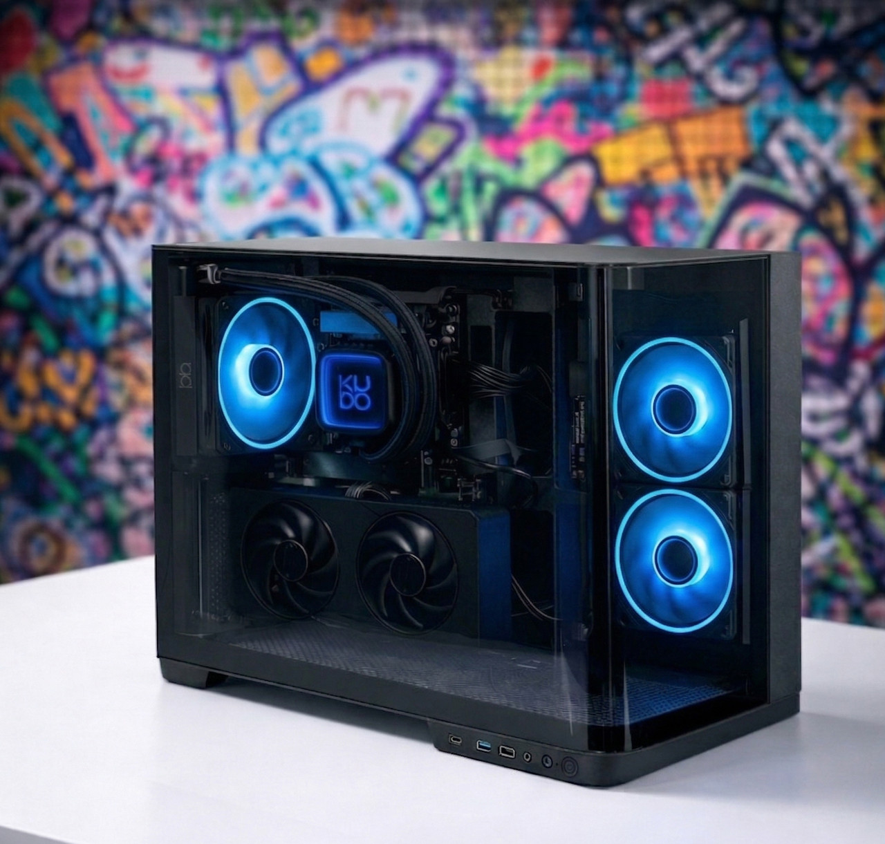 Czarny komputer z niebieskimi światłami stoi przed kolorową ścianą z graffiti.