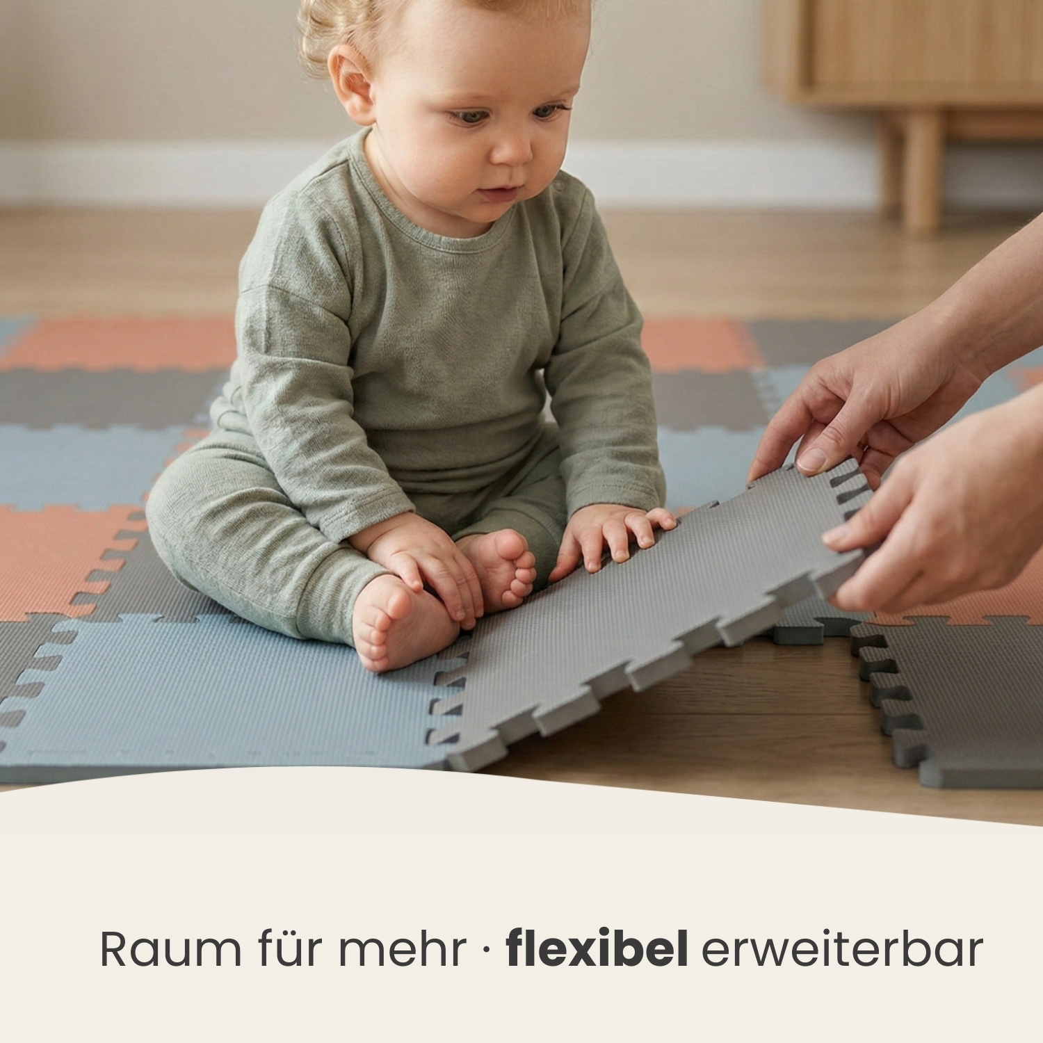 Baby sitzt auf grauen, blauen und rosafarbenen Bodenmatten, Hände legen eine graue Matte aus.