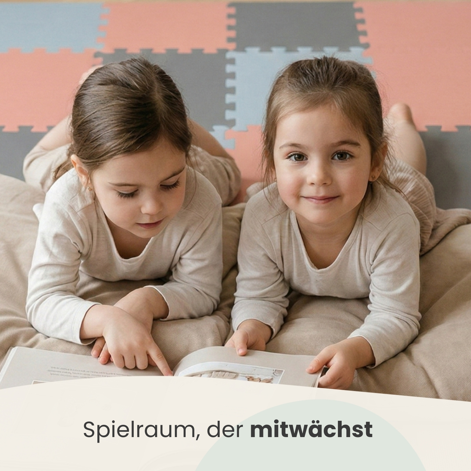 Zwei Mädchen liegen auf einem Teppich und lesen ein Buch.