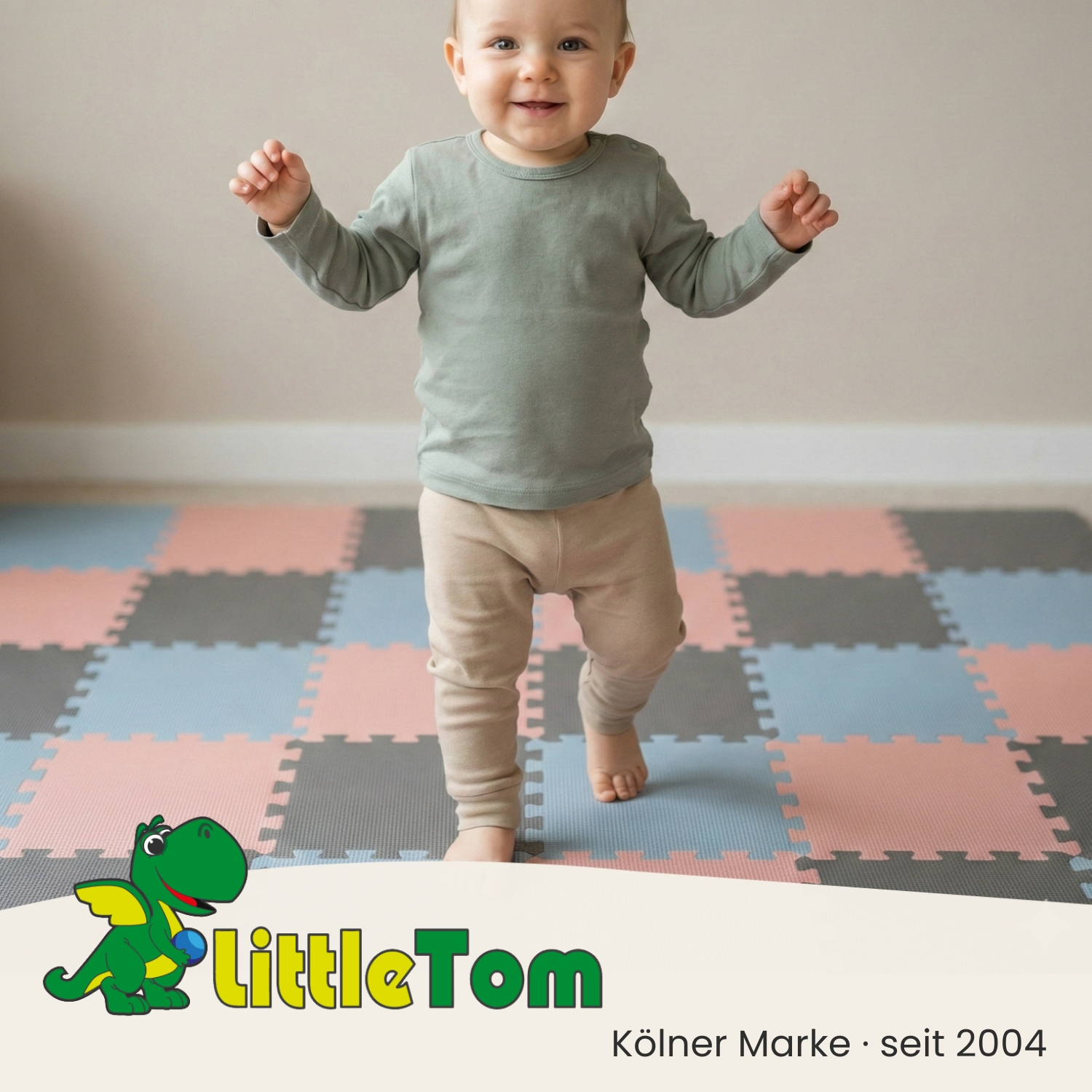 Ein Baby in einem grünen Langarmshirt und beige Hose steht auf einer bunten Spielmatte.