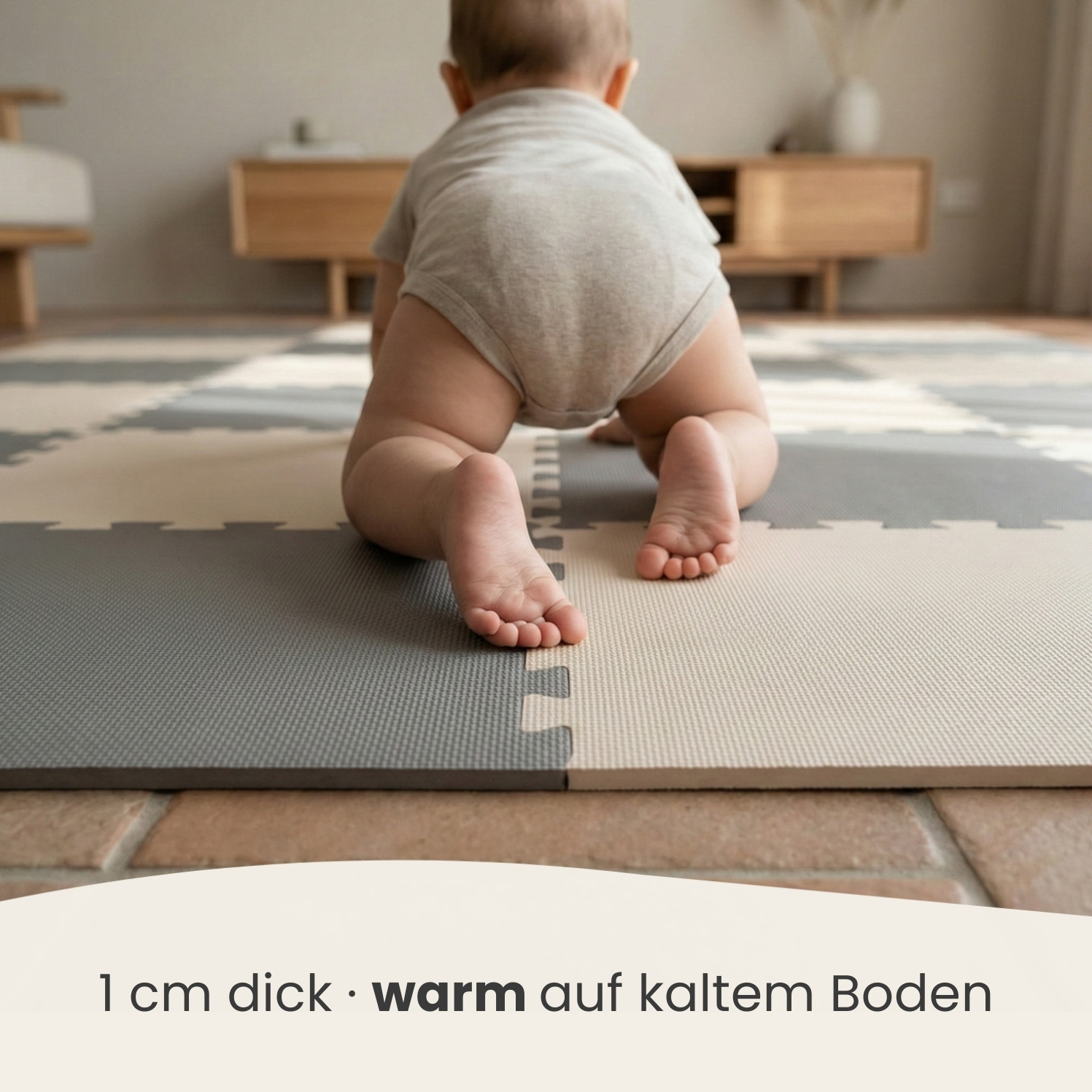 Ein Baby krabbelt auf einer gepolsterten Matte in Grau und Beige.