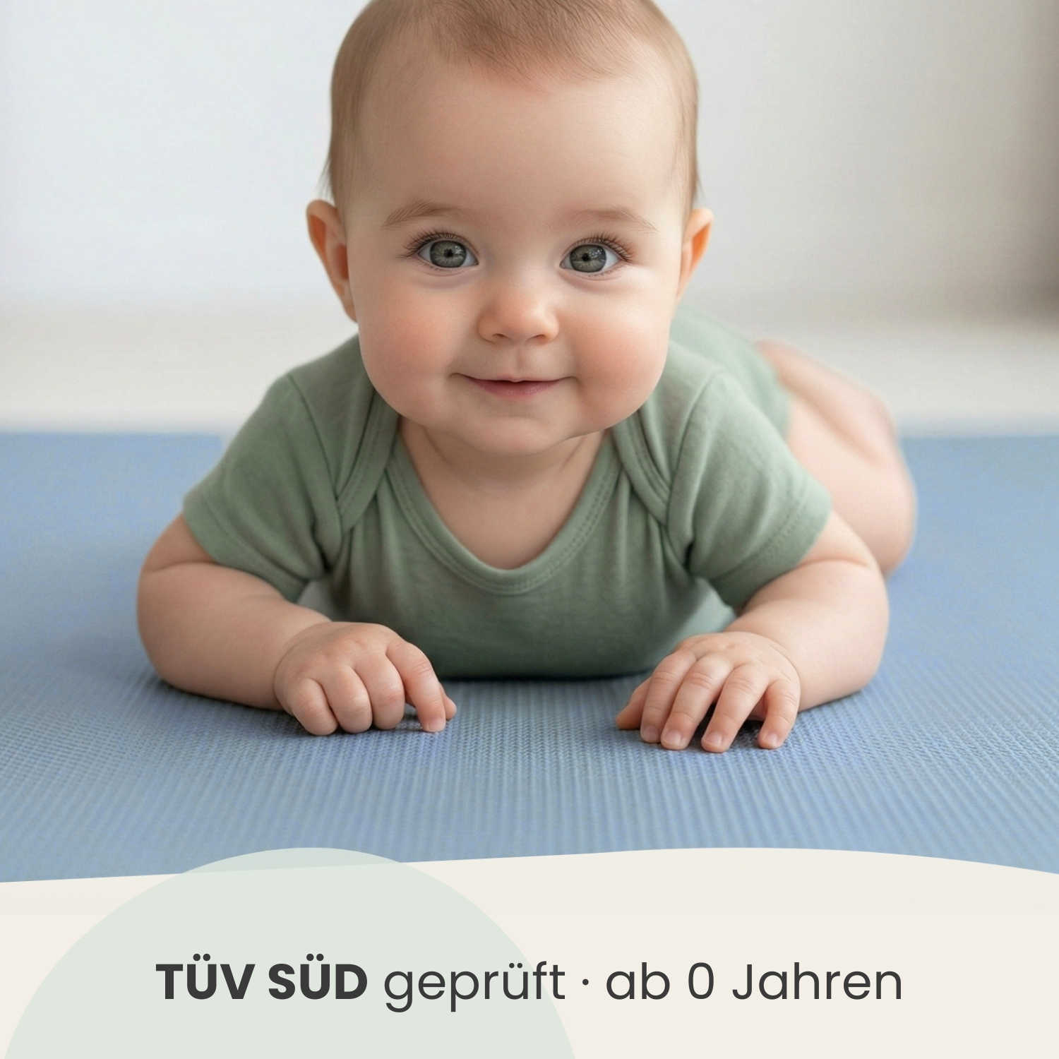 Ein Baby liegt auf dem Bauch auf einer blauen Matte.