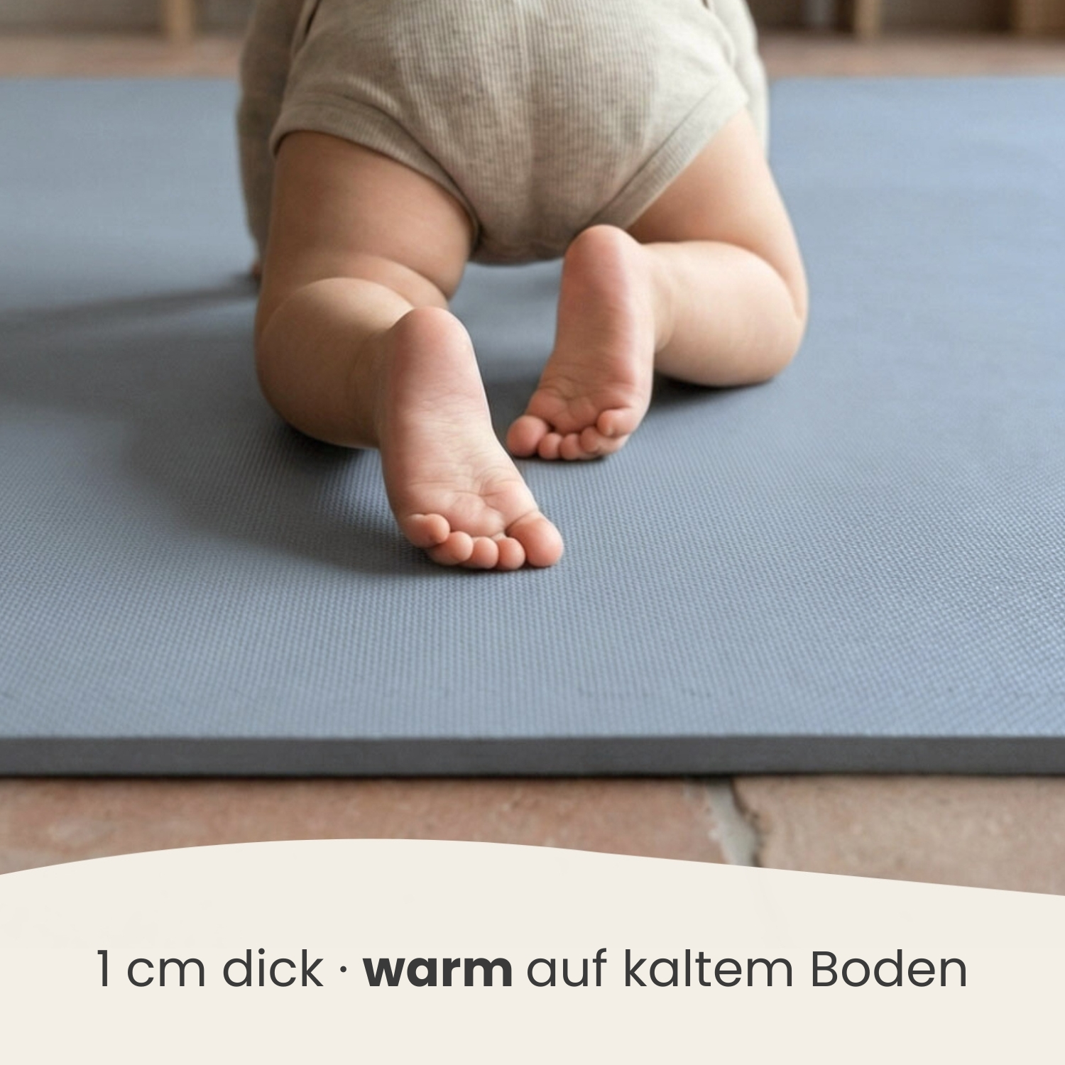 Ein Baby krabbelt auf einer grauen Matte, Nahaufnahme der Füße.