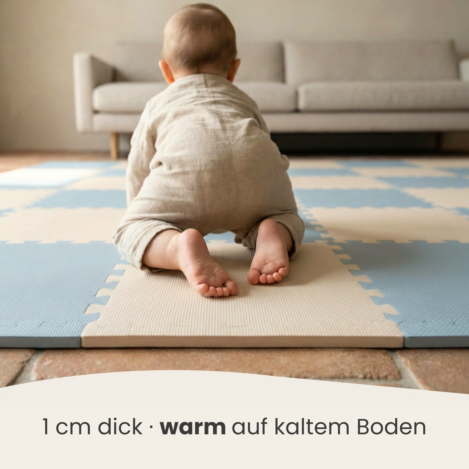 Ein Baby krabbelt auf einer blauen und cremefarbenen Matte vor einem Sofa.