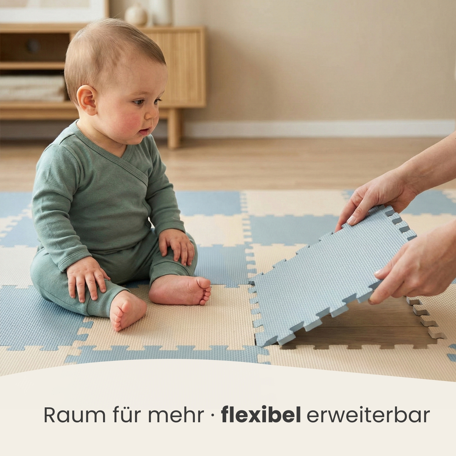 Ein Baby sitzt auf einer hellblauen und beigen Spielmatte, während Hände eine weitere Matte hinzufügen.