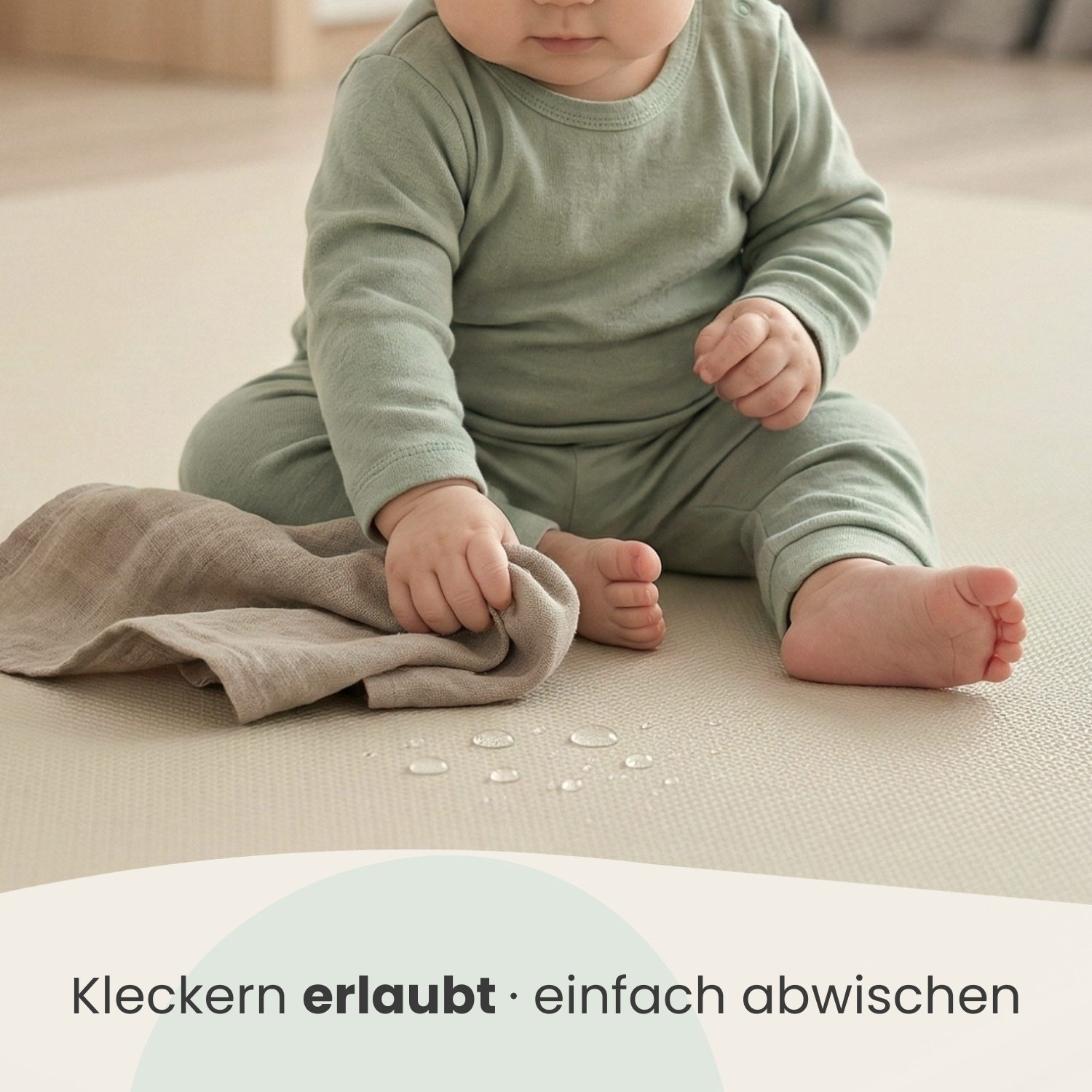 Ein Baby sitzt auf einer hellen Matte, daneben ein Tuch und Wassertropfen.