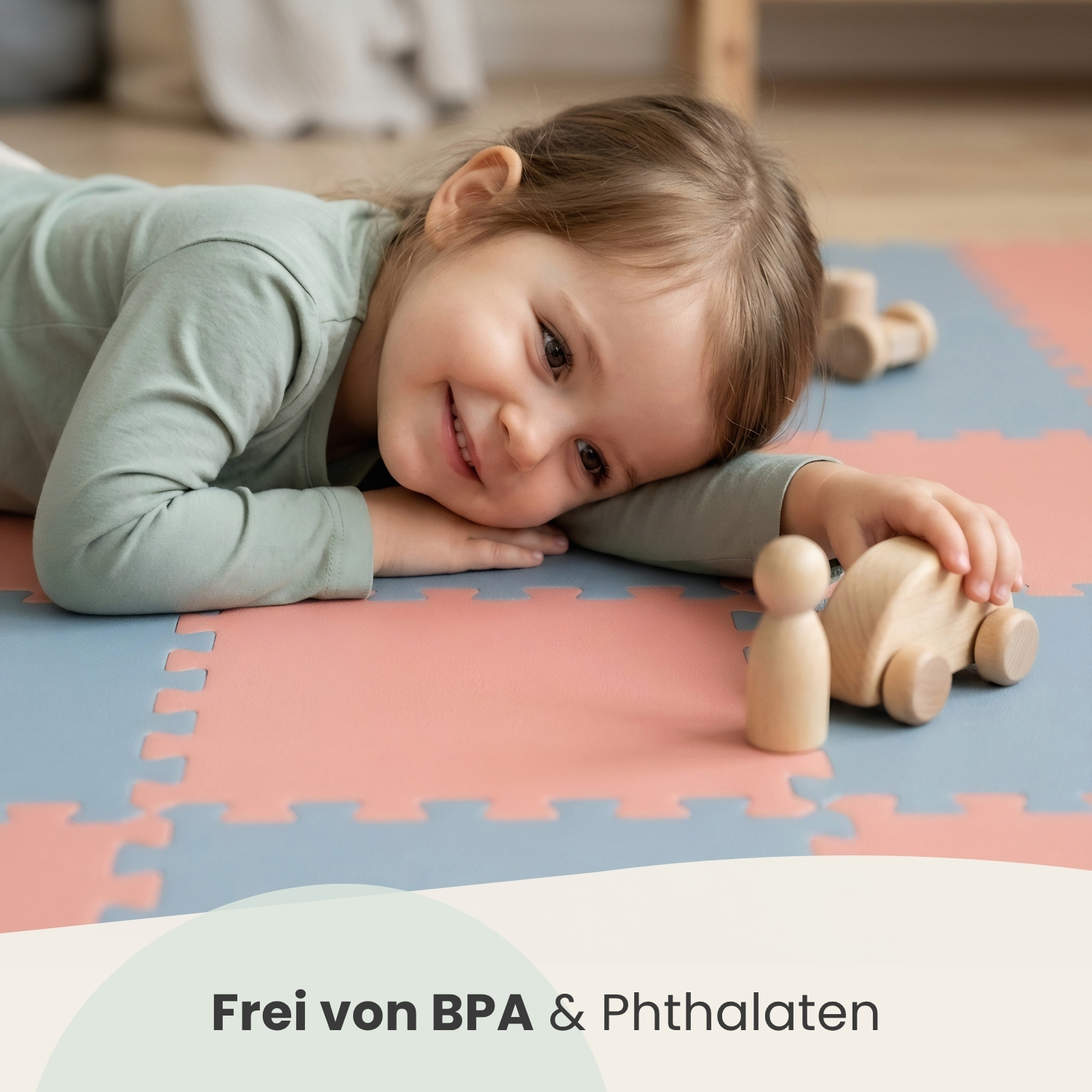 Ein kleines Mädchen liegt auf einer Spielmatte und lächelt in die Kamera.
