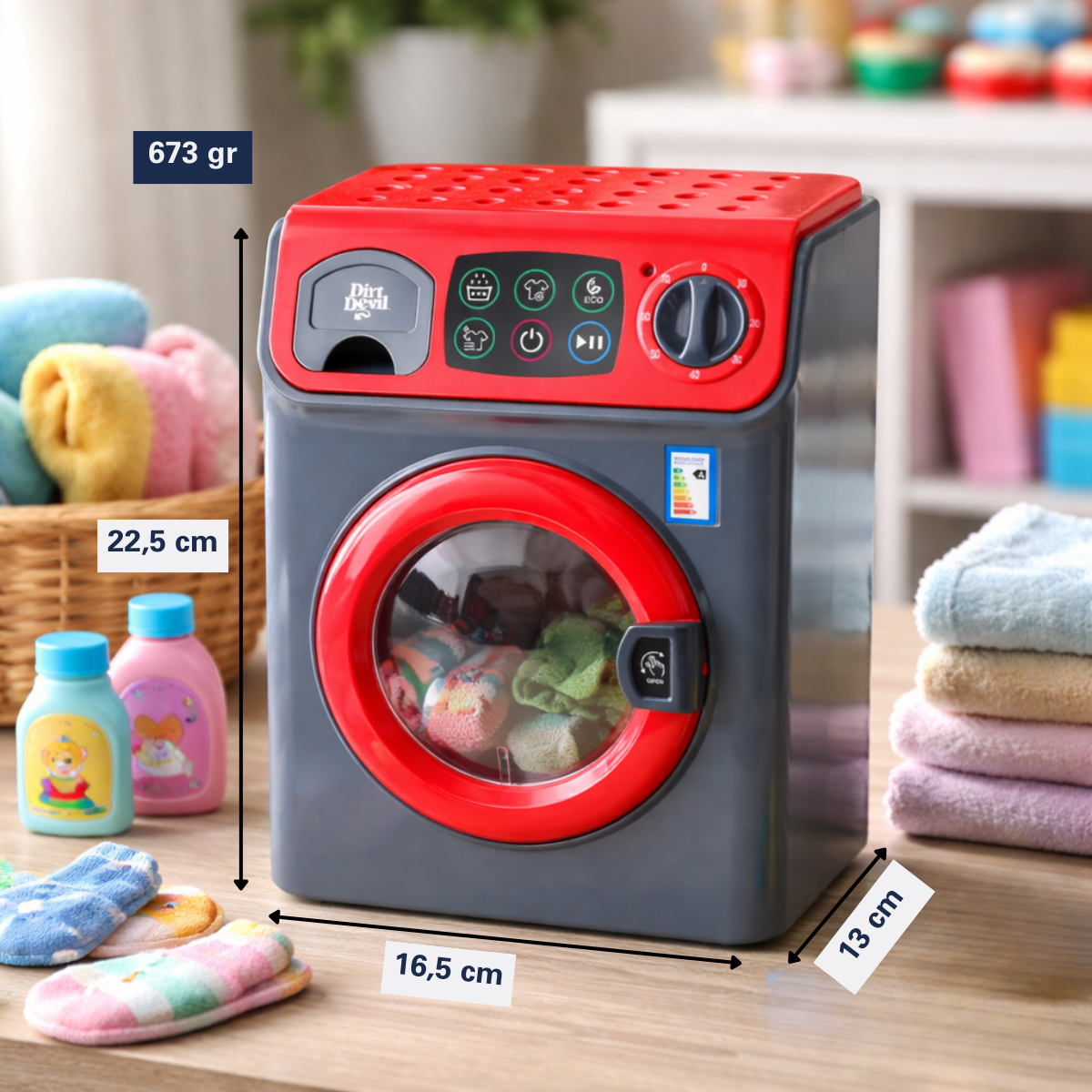 Gray and red toy washing machine with clothes, flanked by detergent bottles and towels.