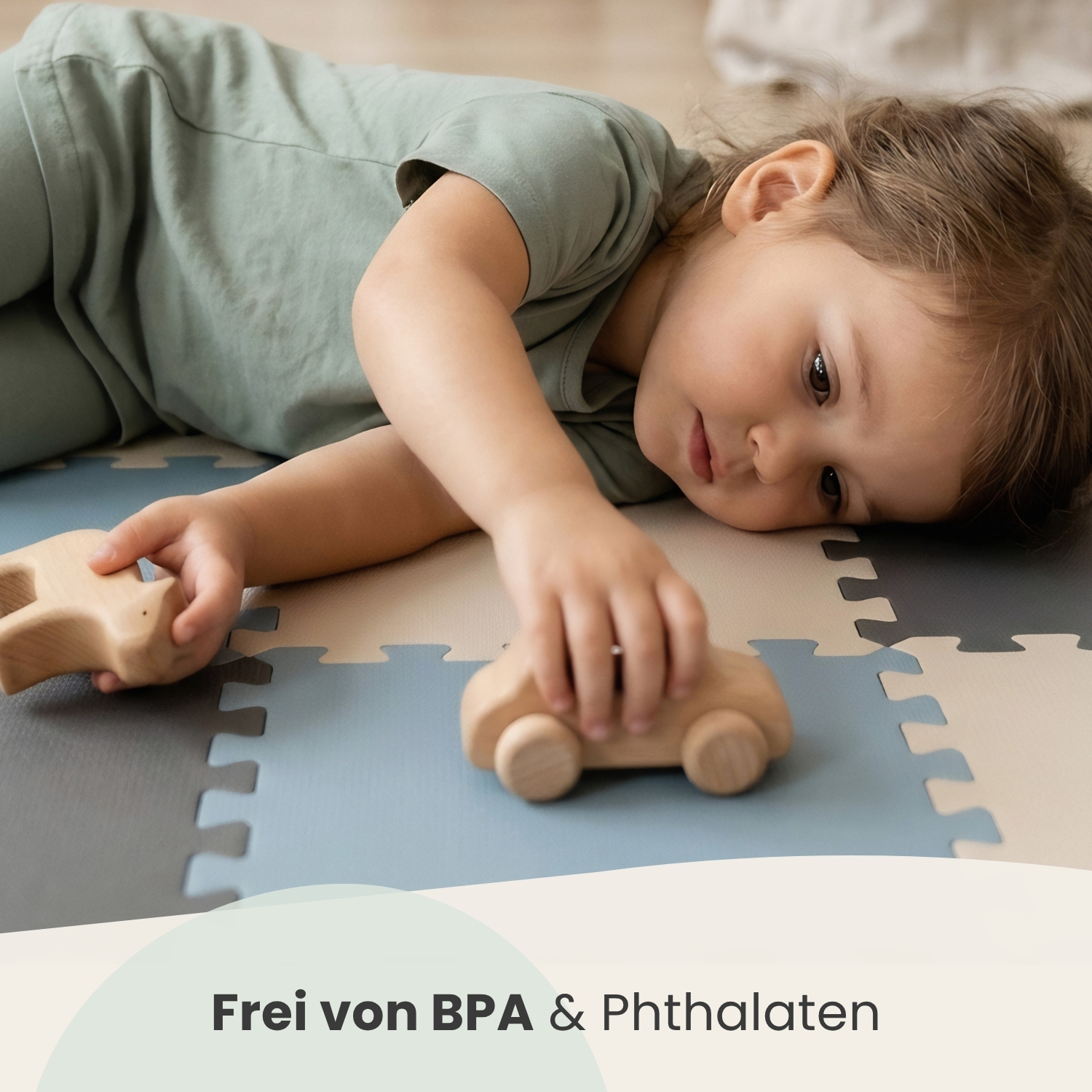 Ein Kind liegt auf einer Puzzlematte und spielt mit Holzautos.