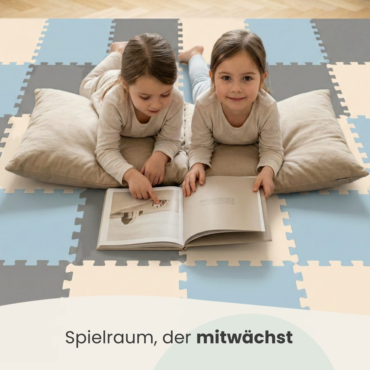 Zwei Mädchen liegen auf einem bunten Teppich und lesen ein Buch.