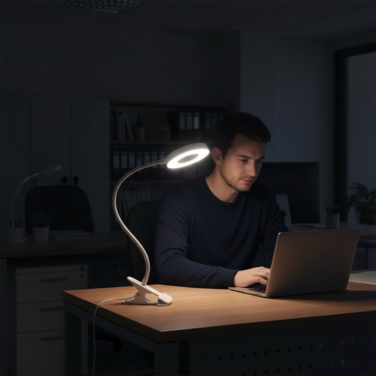 Ein Mann arbeitet nachts an einem Laptop, beleuchtet von einer Schreibtischlampe.