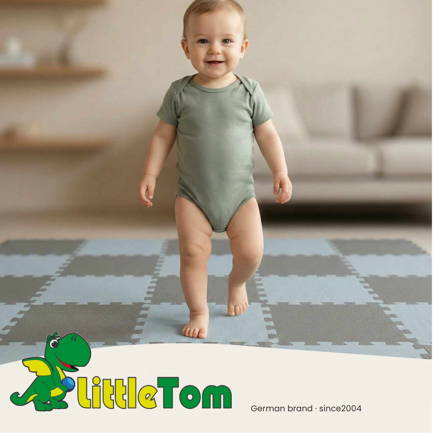 Ein Baby in einem grünen Body steht auf einem Teppich aus grauen und blauen Kacheln.