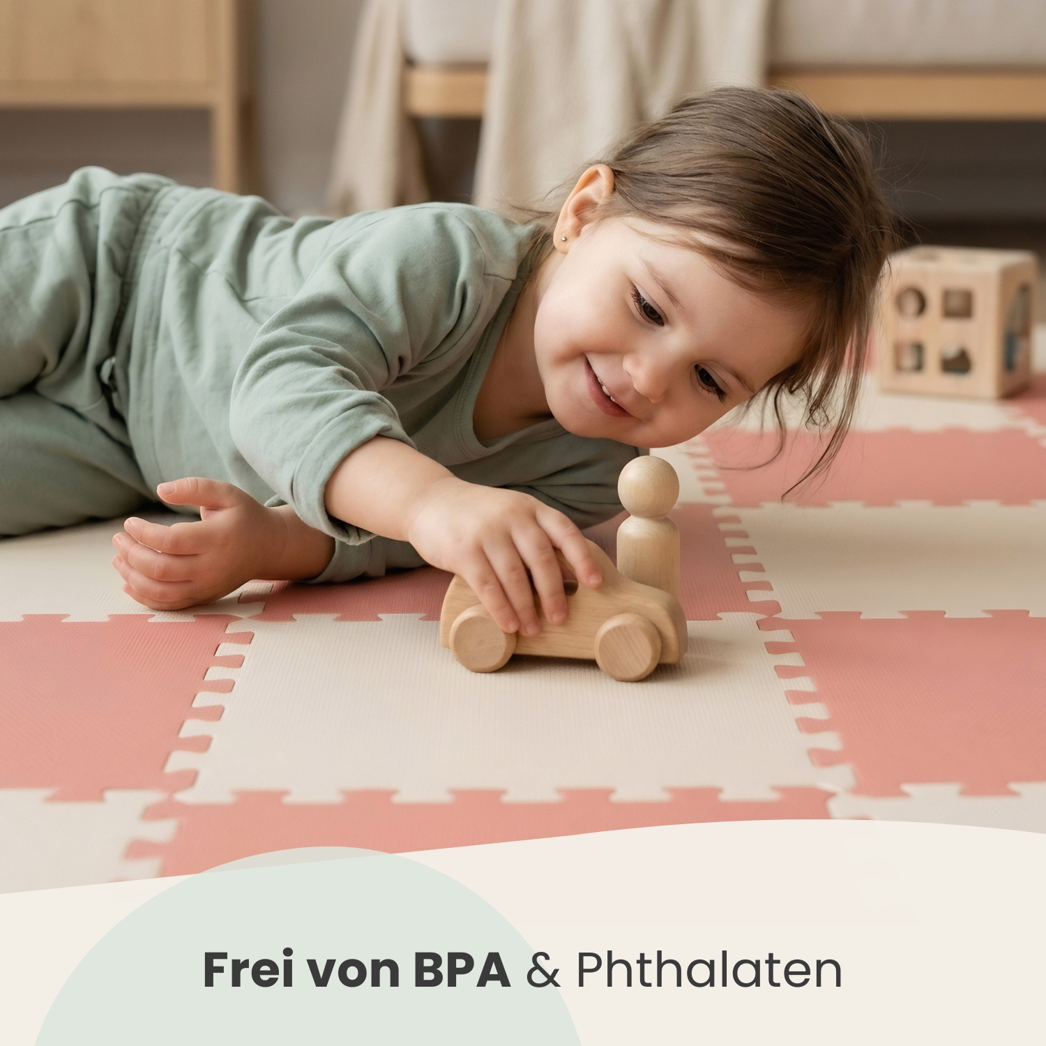 Ein kleines Mädchen spielt mit einem Holzspielzeugzug auf einer weichen Matte.