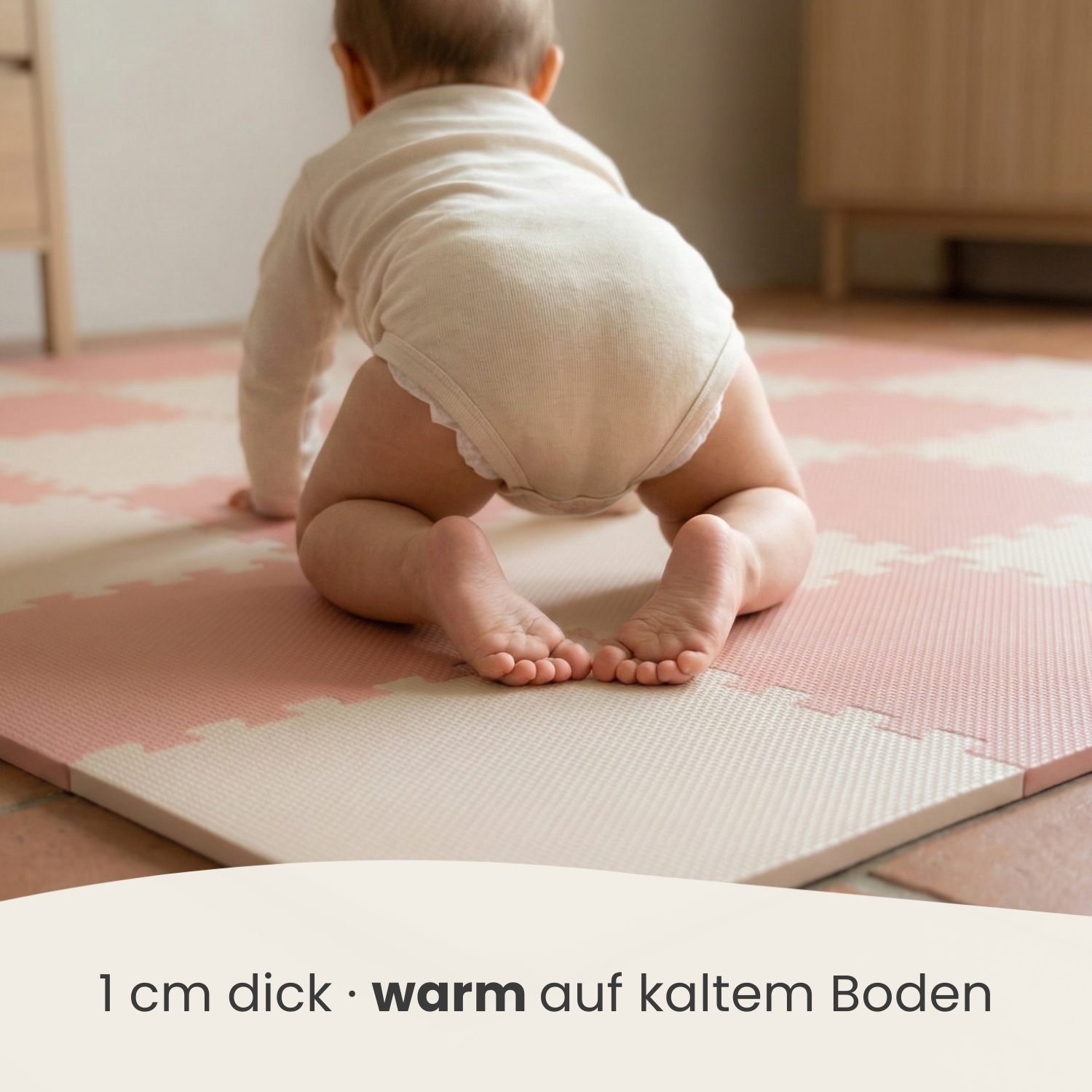 Baby krabbelt auf einer weichen, gepolsterten Matte in Rosa- und Beigetönen.
