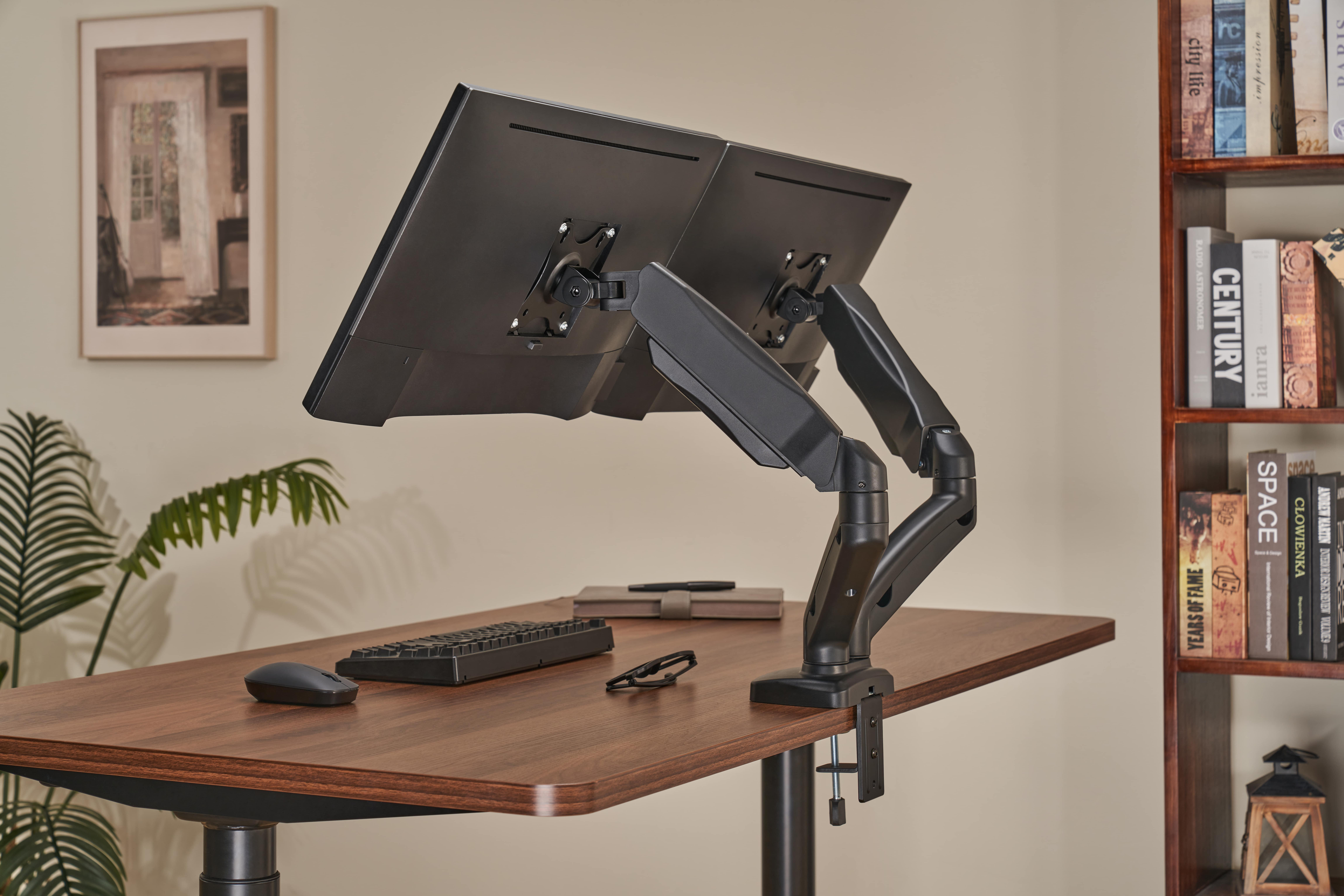 Ein Schreibtisch mit zwei Monitoren, Tastatur, Maus, Notizbuch und Brille.