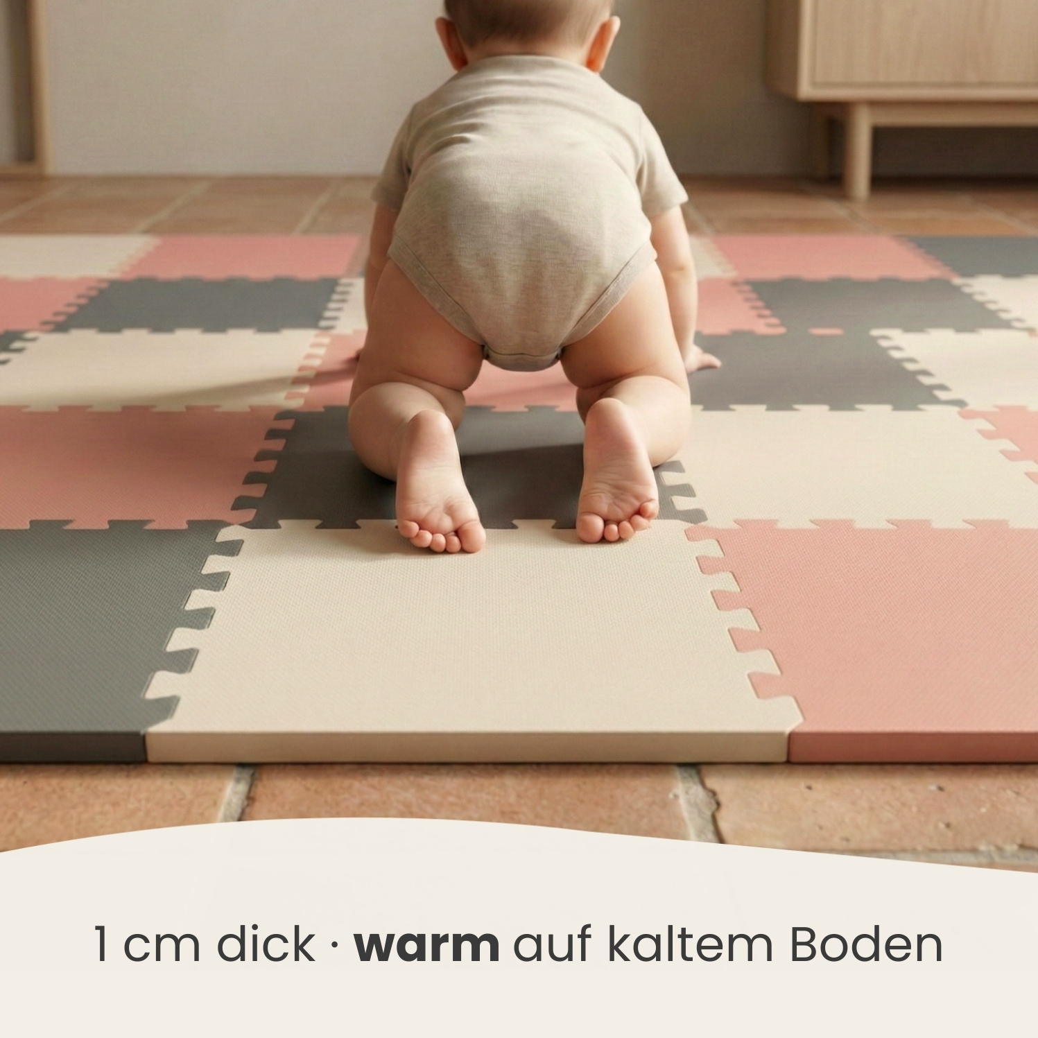 Baby krabbelt auf einem bunten Puzzle-Teppichboden in Rosa, Grau und Beige.