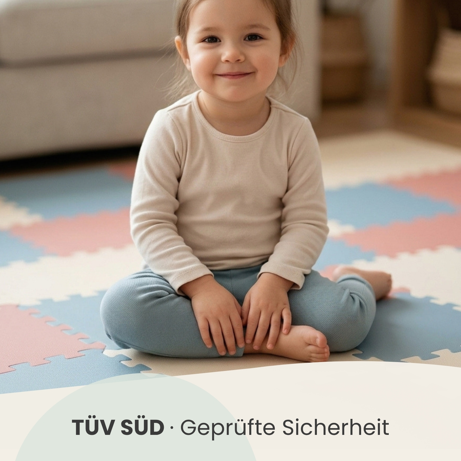 Ein kleines Mädchen sitzt lächelnd auf einer bunten Matte. TÜV SÜD Logo.