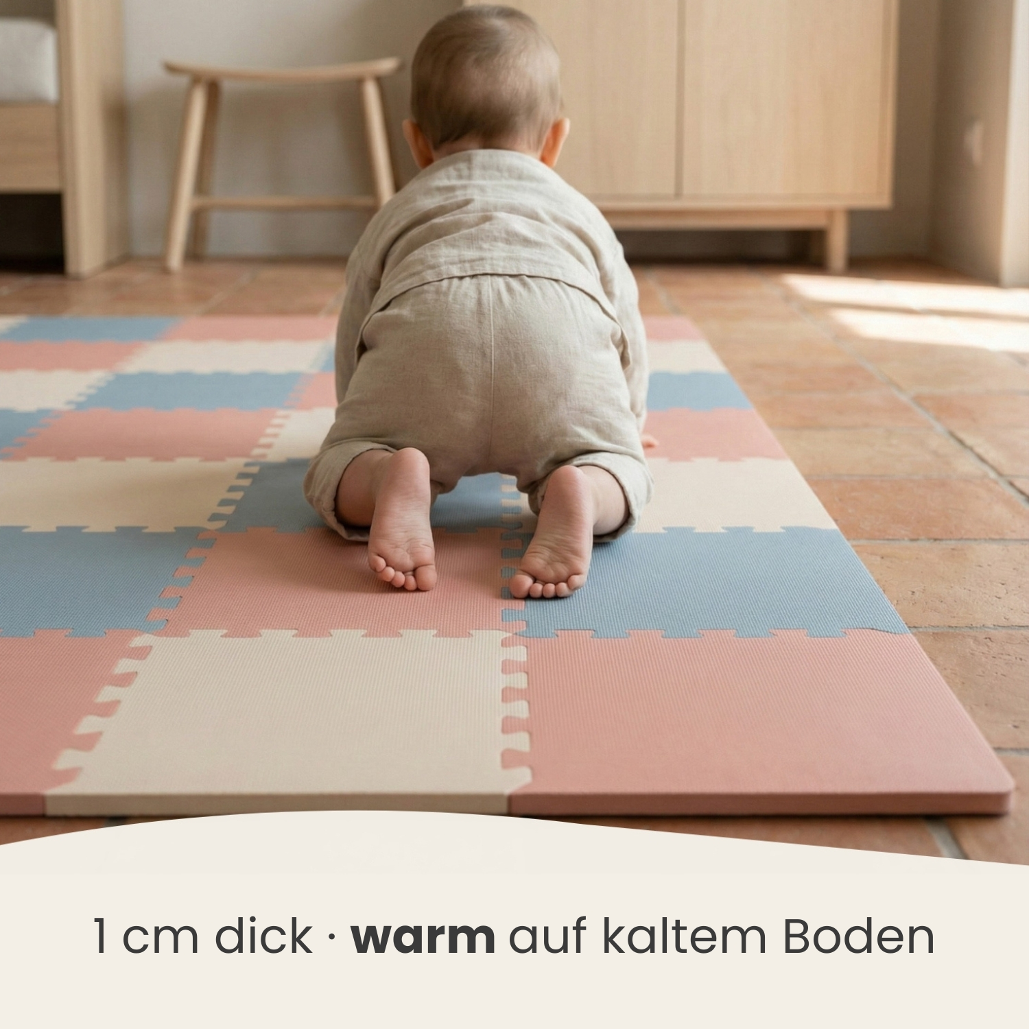 Baby krabbelt auf einer bunten Matte. Beige, rosa, blaue Felder.