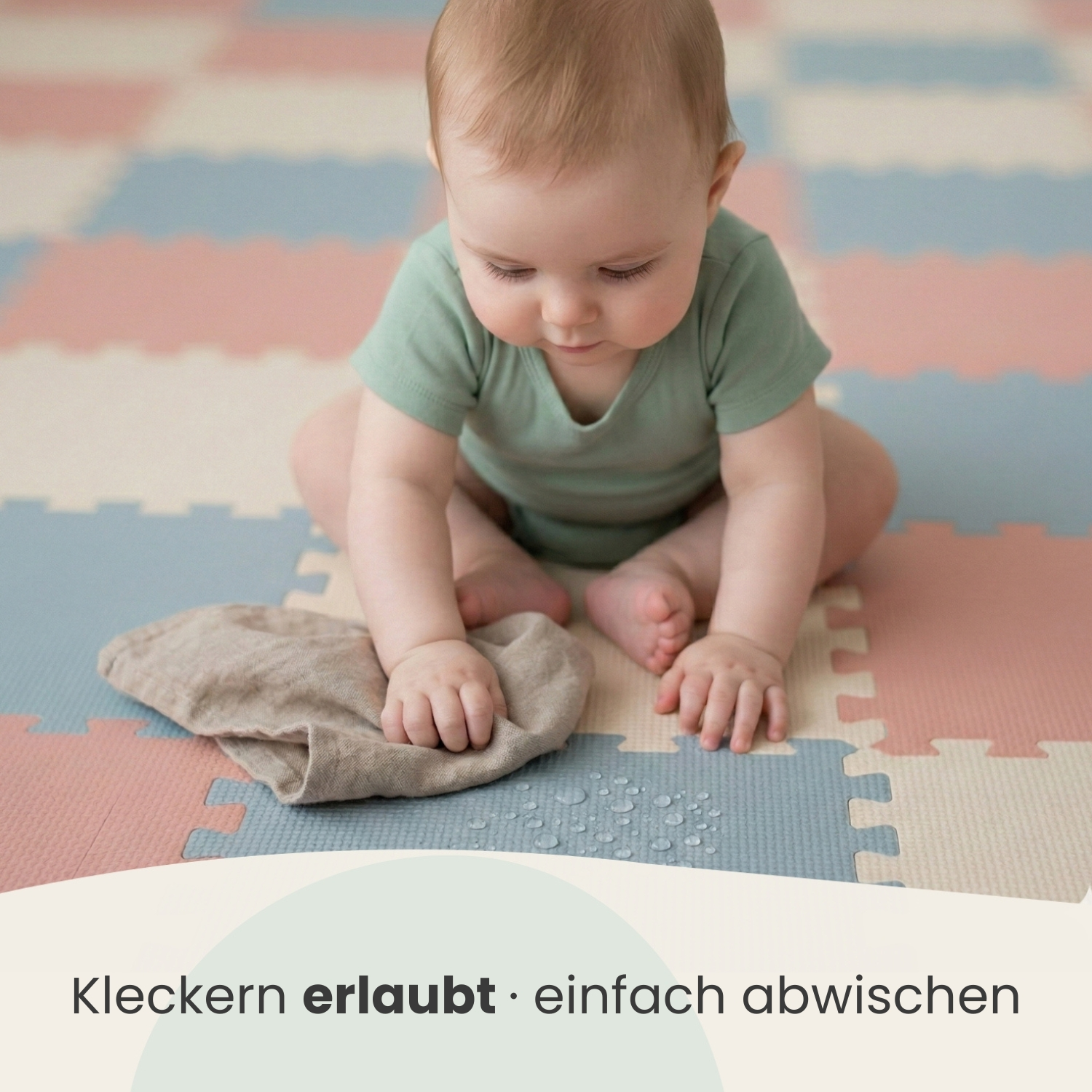Ein Baby sitzt auf einer bunten Matte und spielt mit einem Stofftuch, auf dem Wasserflecken sind.