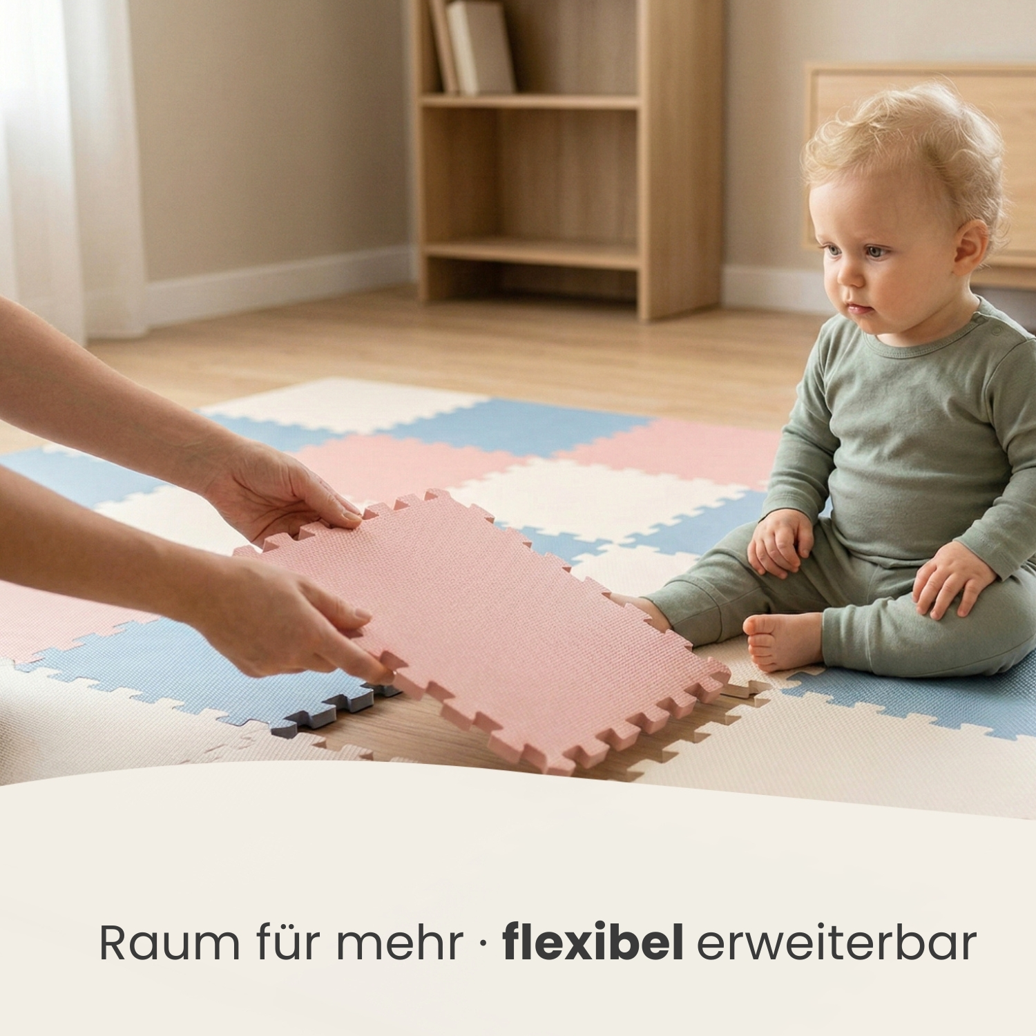Ein Baby sitzt auf einer Spielmatte, die von einer Person erweitert wird.