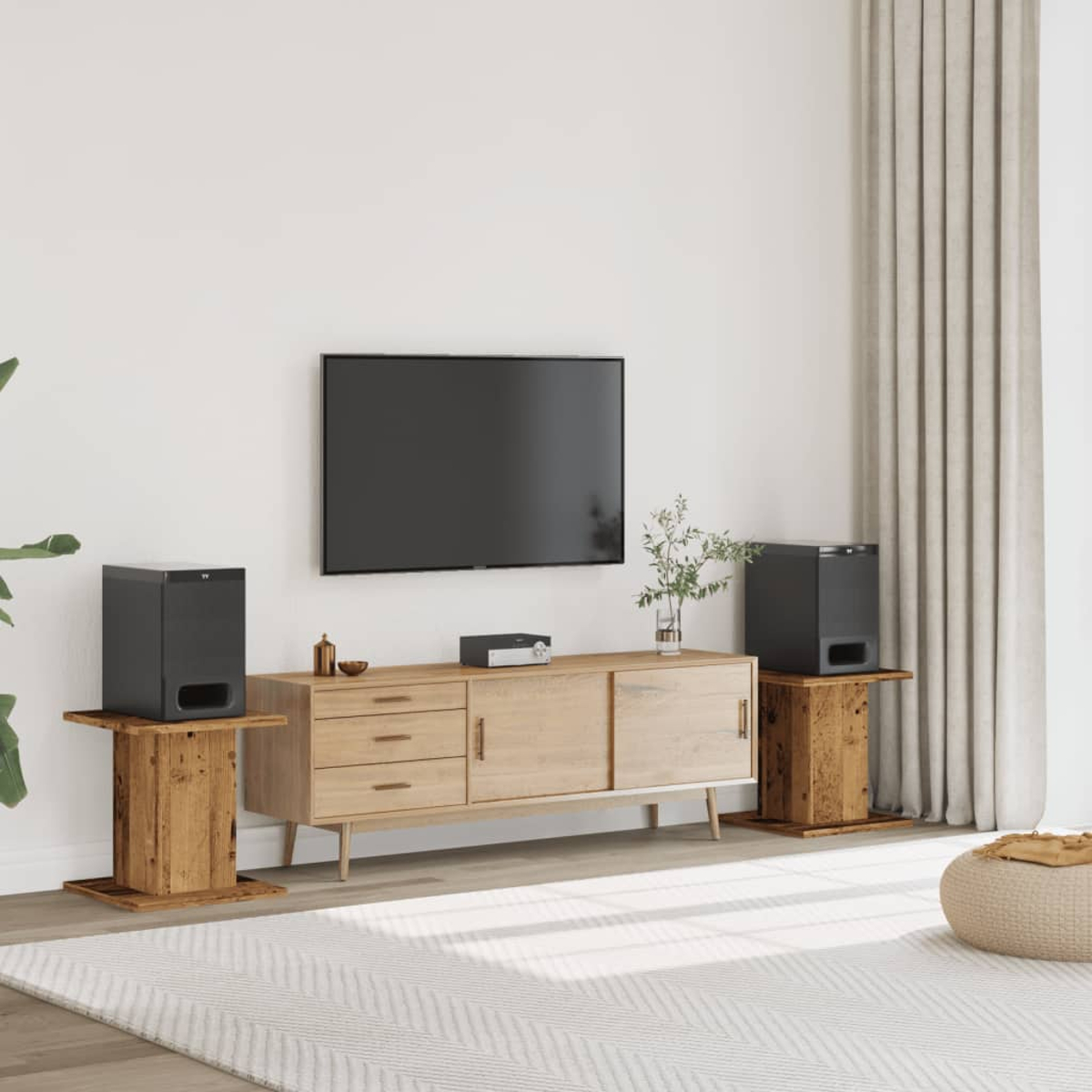 Ein großer schwarzer Fernseher hängt über einem hellbraunen Sideboard mit Geräten und Dekoration.