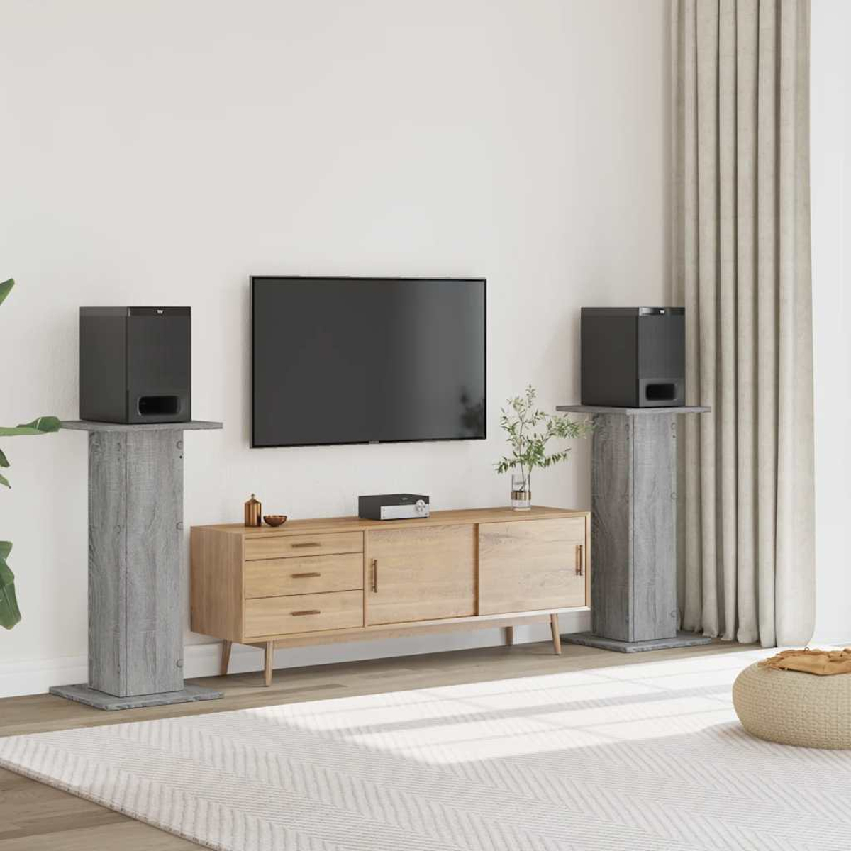 Ein Wohnzimmer mit TV, Sideboard, zwei Lautsprecherständern und einem Teppich.