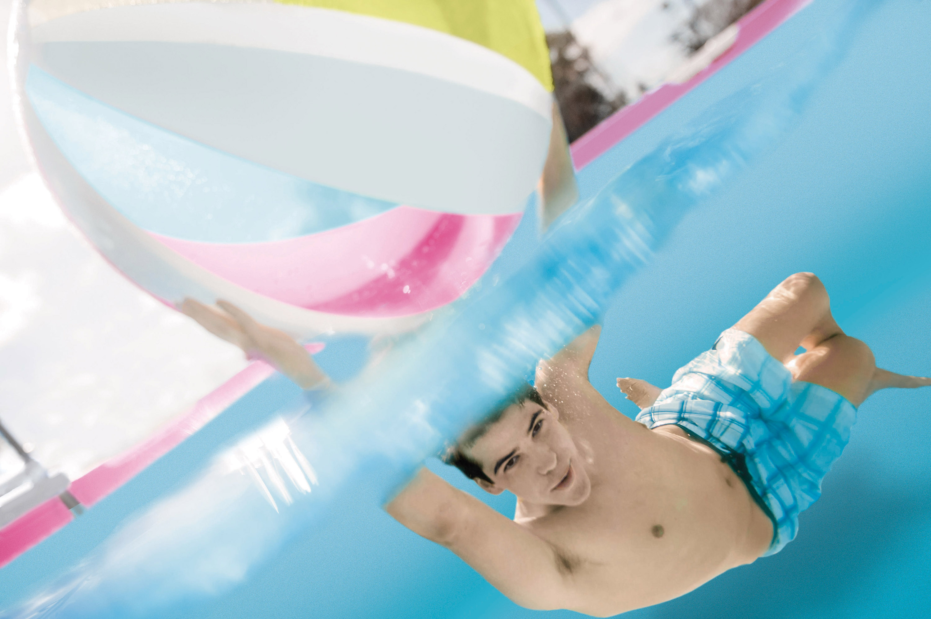 Ein Junge schwimmt unter Wasser mit einem bunten Ball.