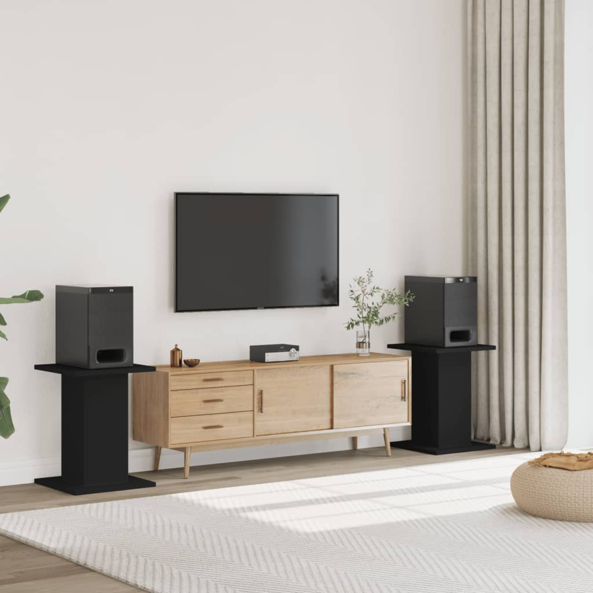 Ein Wohnzimmer mit TV, Mediakonsole, zwei Lautsprechern auf Ständern und Vorhängen.
