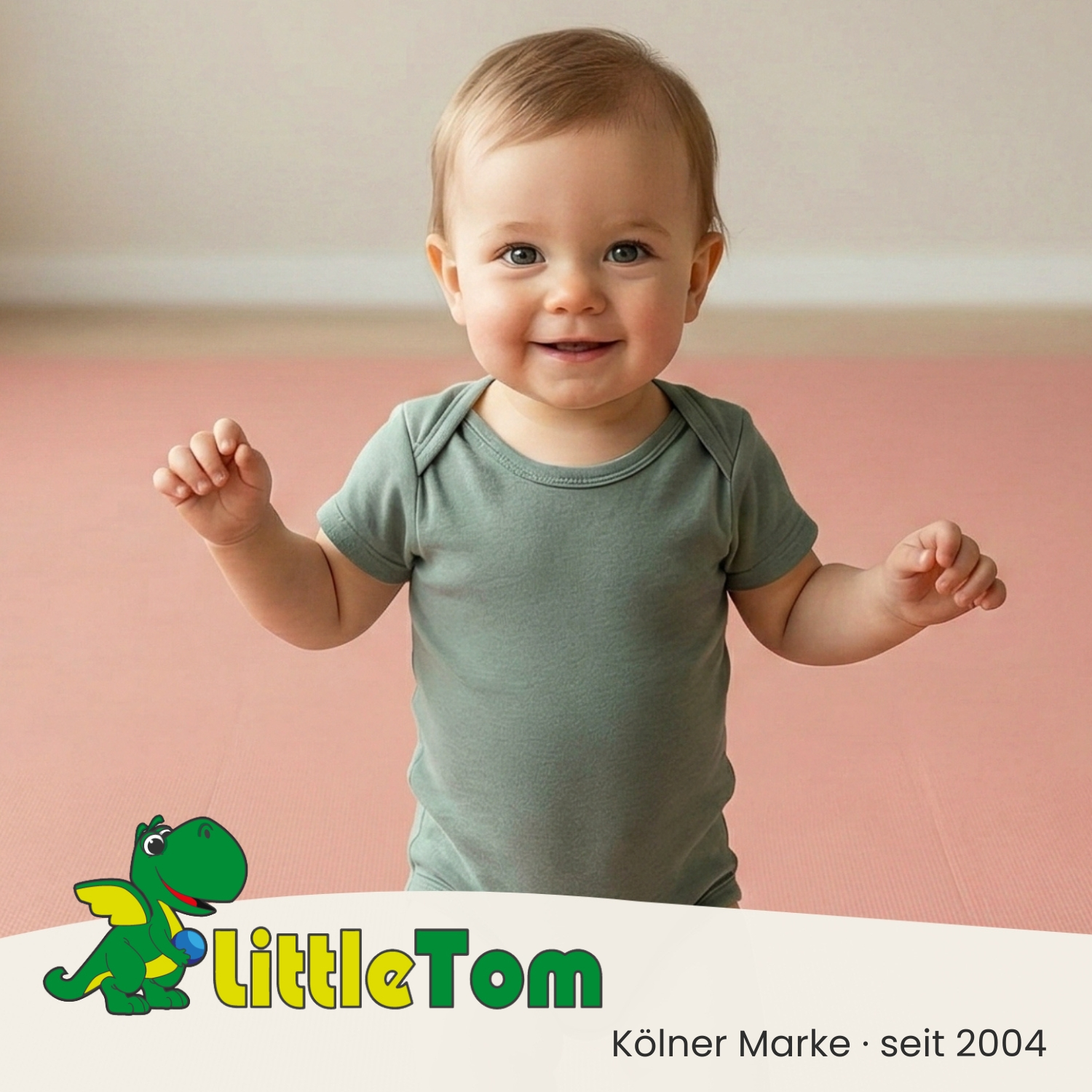 Ein Baby in einem grauen Body lächelt und hält die Arme ausgestreckt.