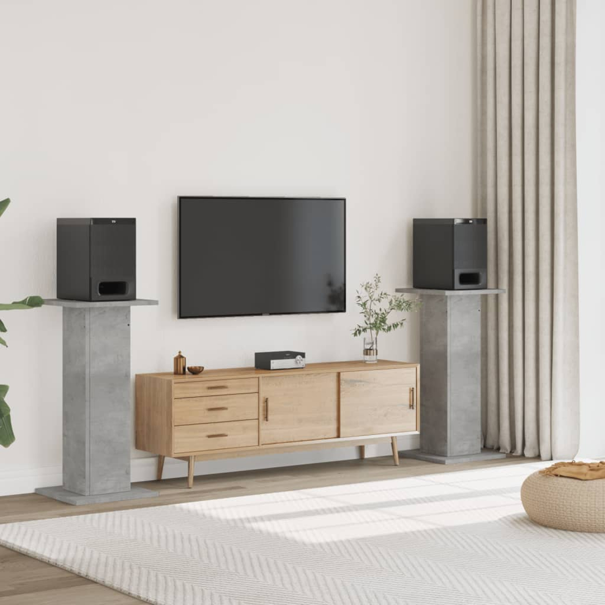 Ein Wohnzimmer mit Fernseher, Sideboard, Lautsprechern auf Ständern und Teppich.