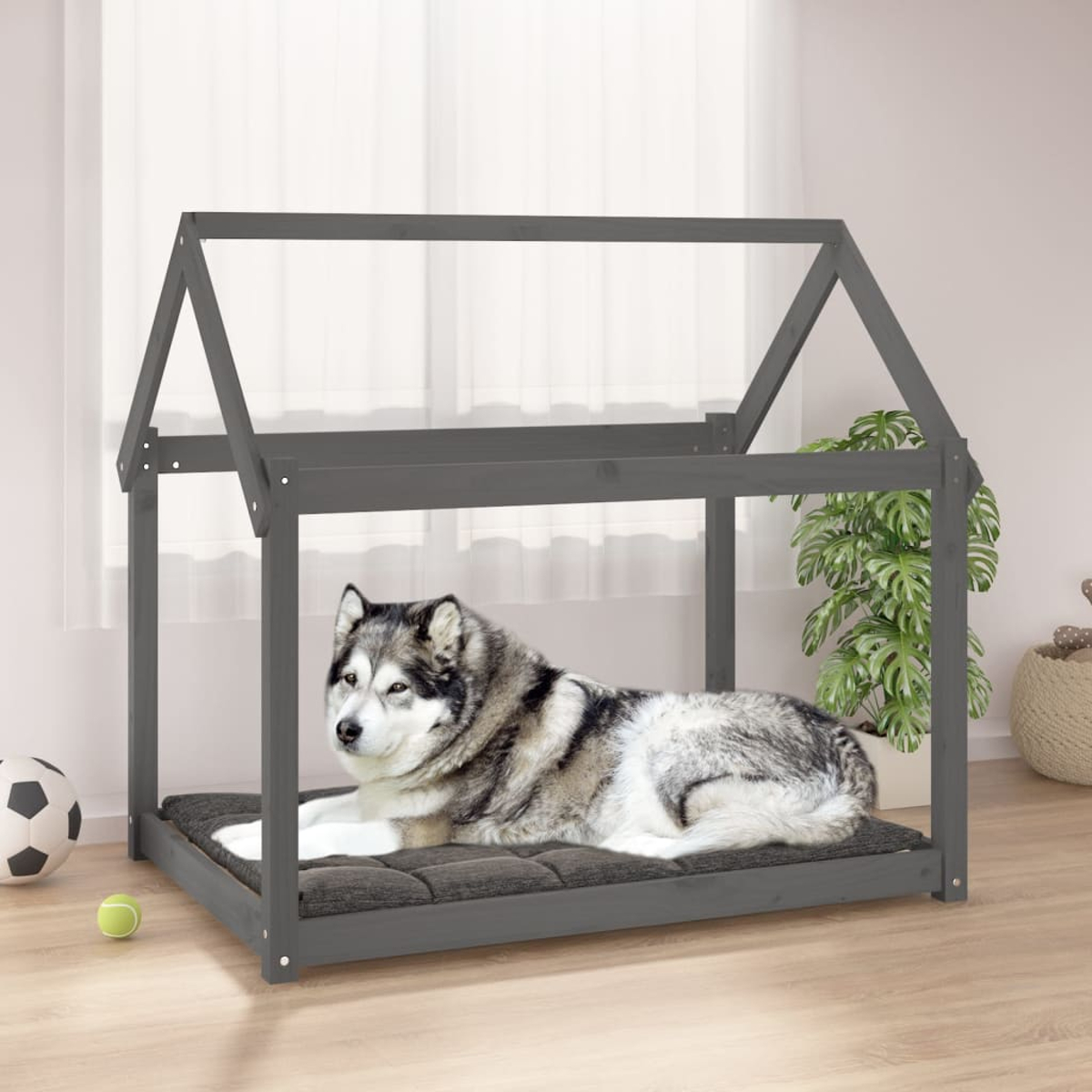 Ein Husky liegt auf einem grauen Kissen in einem dunklen Hundebett im Hausstil.