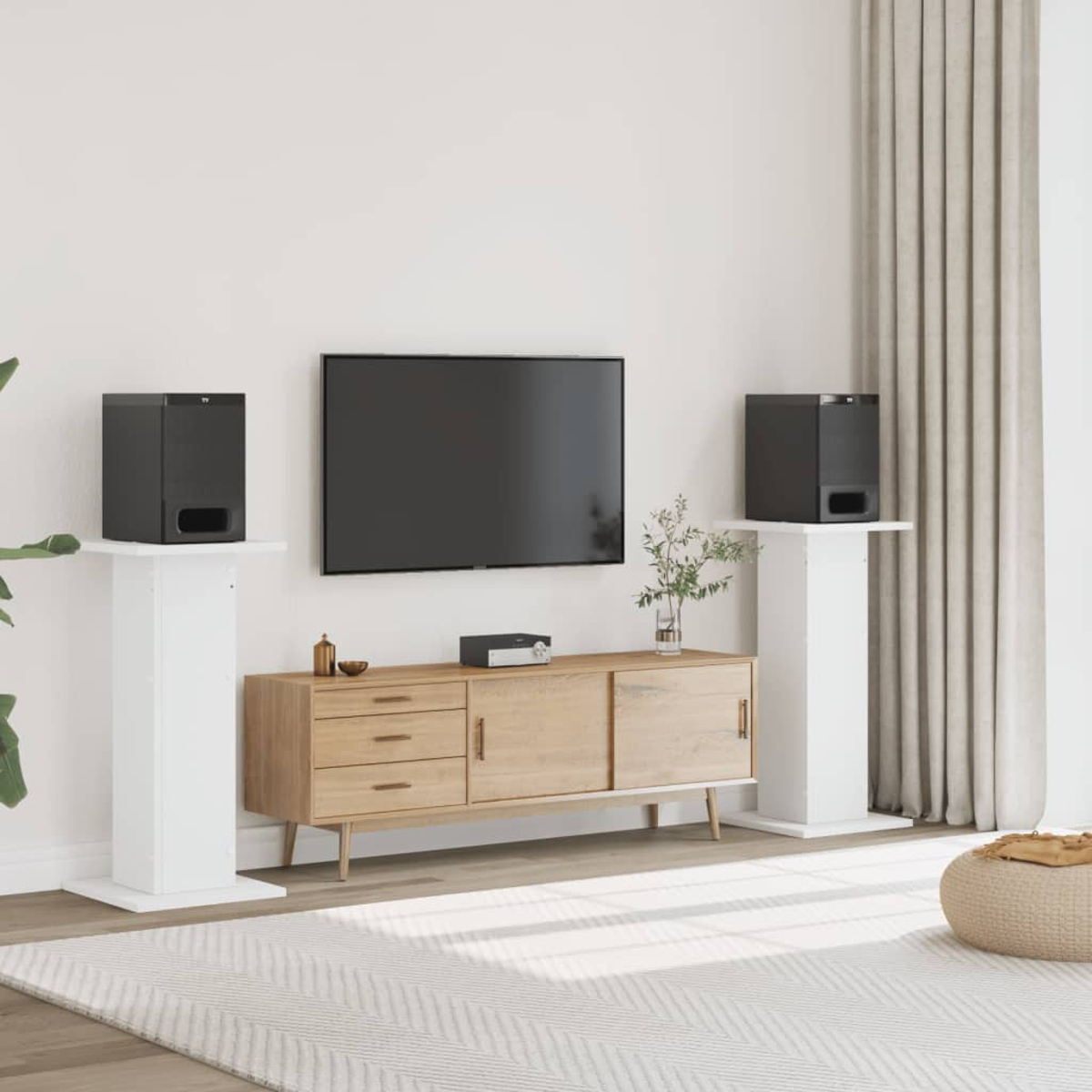 Ein schwarzer Fernseher ist über einem Holzschrank montiert. Zwei schwarze Lautsprecher stehen auf weißen Podesten.