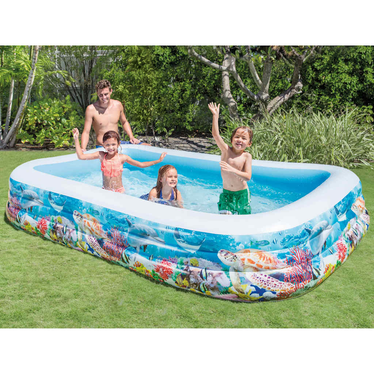 Familia juega en piscina inflable con gráficos oceánicos. Césped rodea la piscina.
