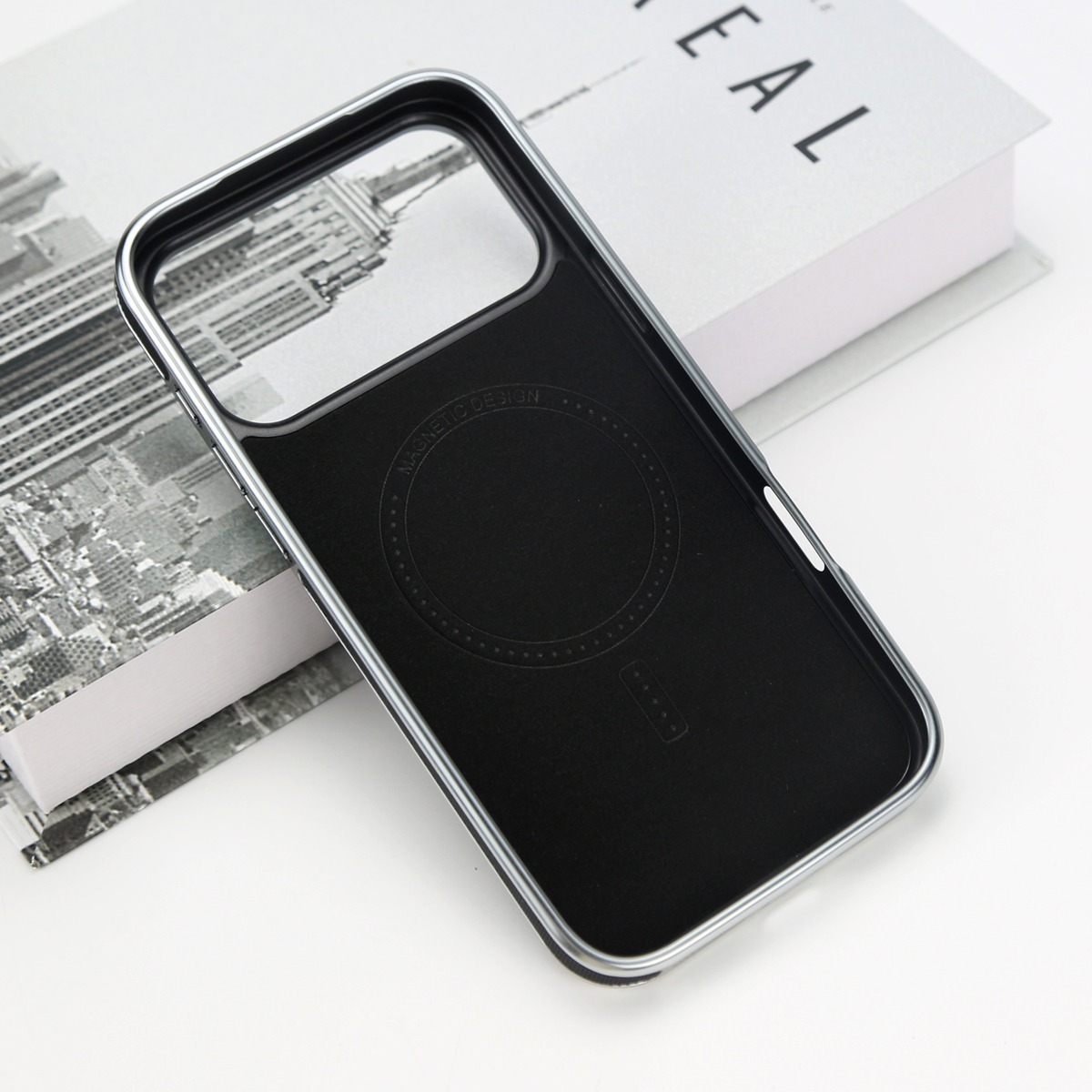 Cover nera per telefono con bordo argento su un libro.