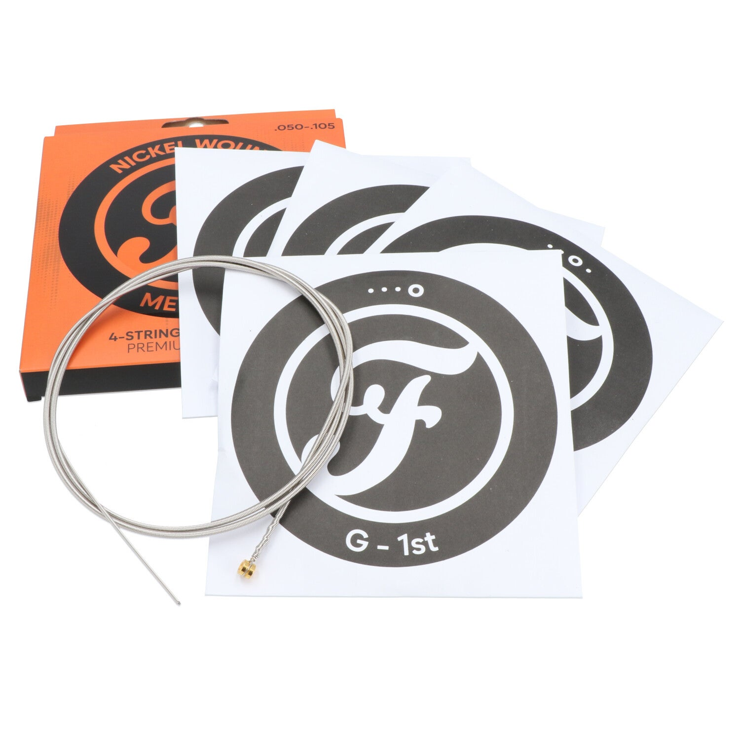 Een enkele gitaarsnaar ligt op een stapel ronde stickers naast een oranje verpakking.