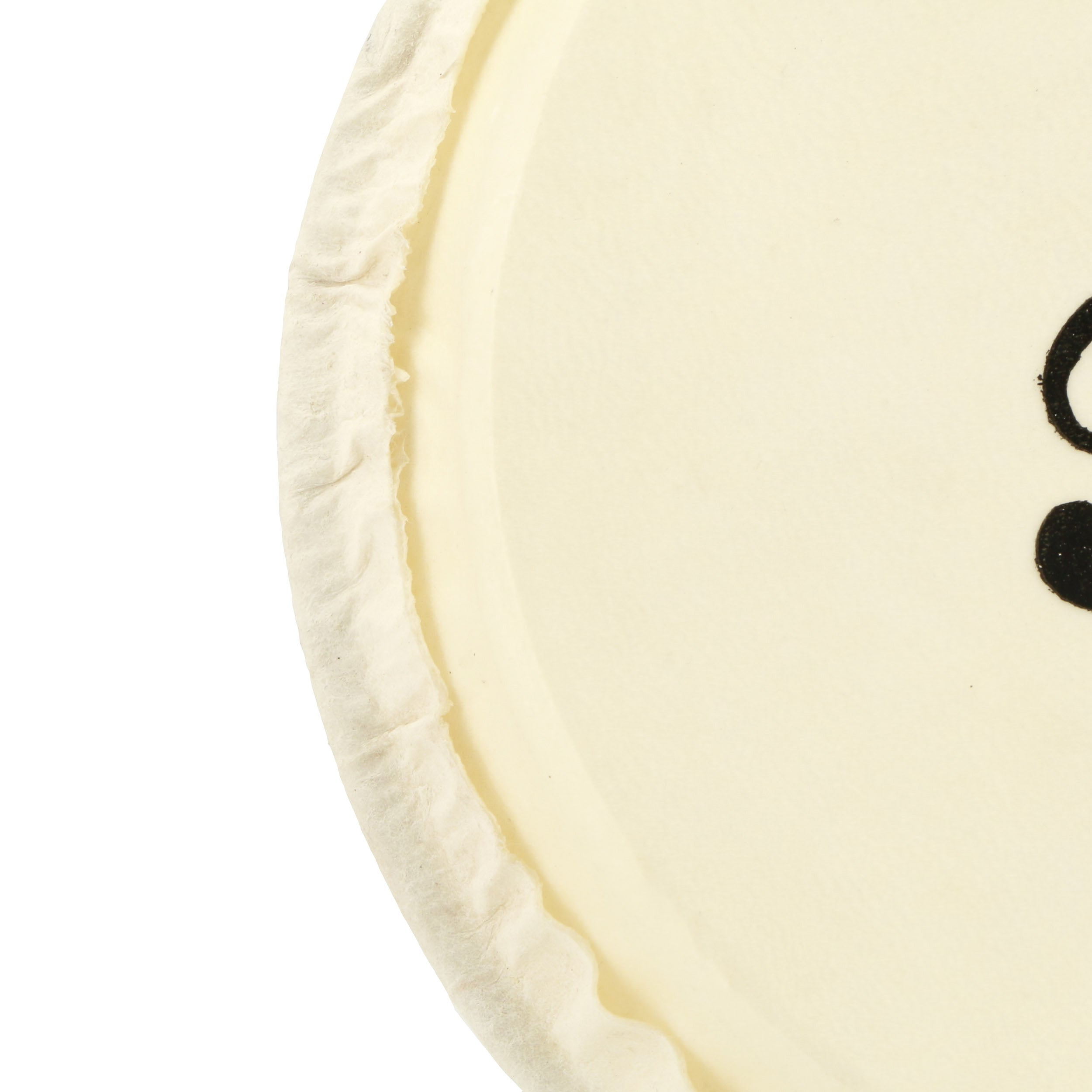 Close-up van een crèmekleurige cirkel met zwart puntpatroon.