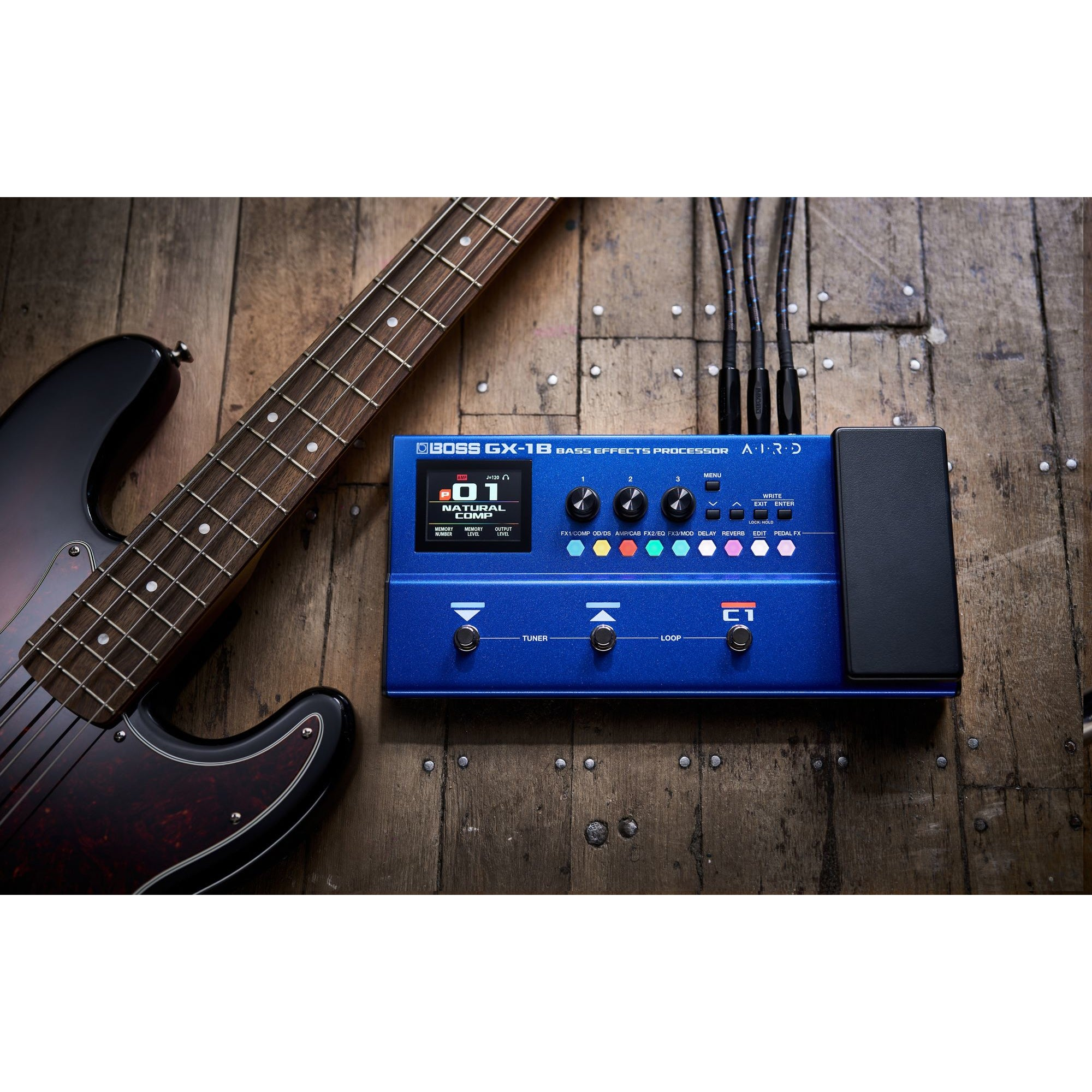 Een blauwe bas-effectprocessor naast een zwarte basgitaar op hout.