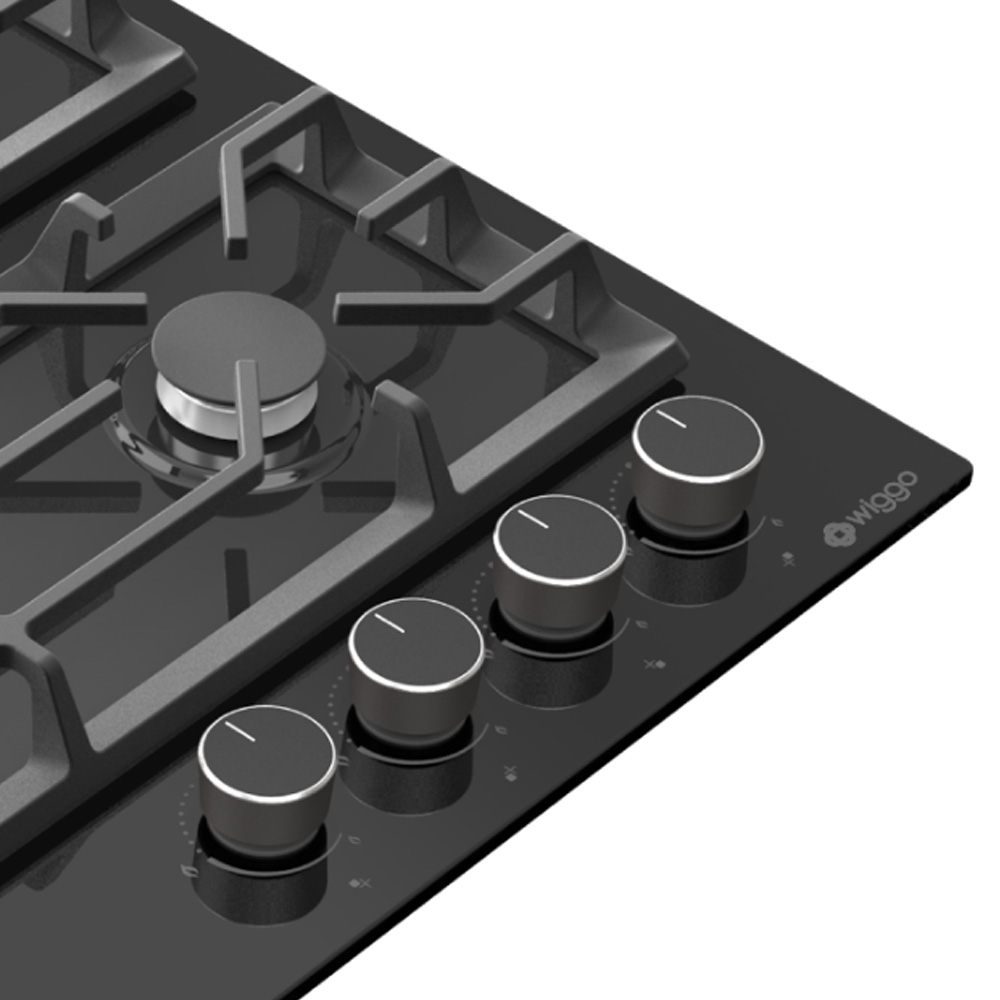 Close-up of a black gas stovetop with four silver knobs and a grate.