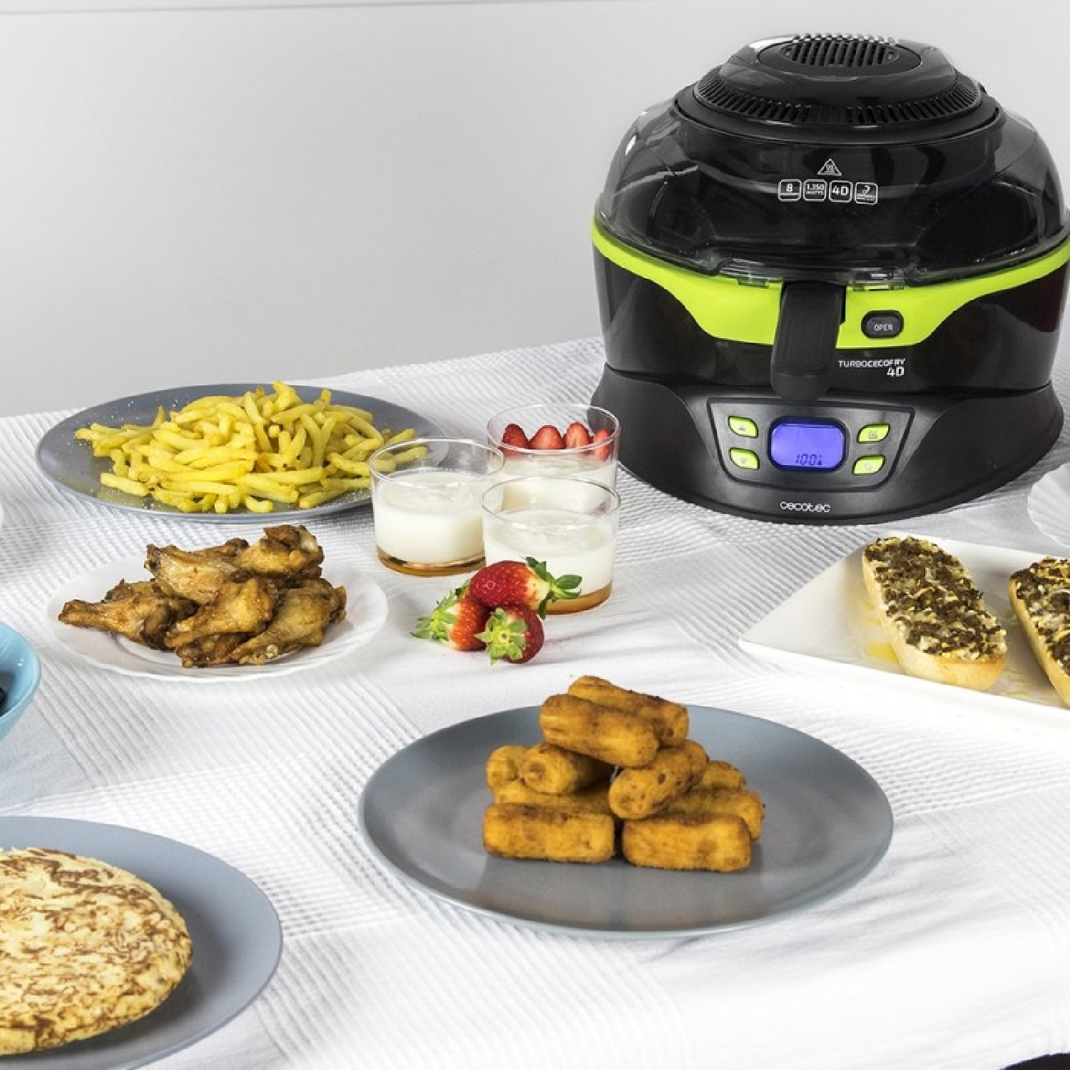 Una freidora de aire con patatas fritas, alitas de pollo, pasteles y pan.