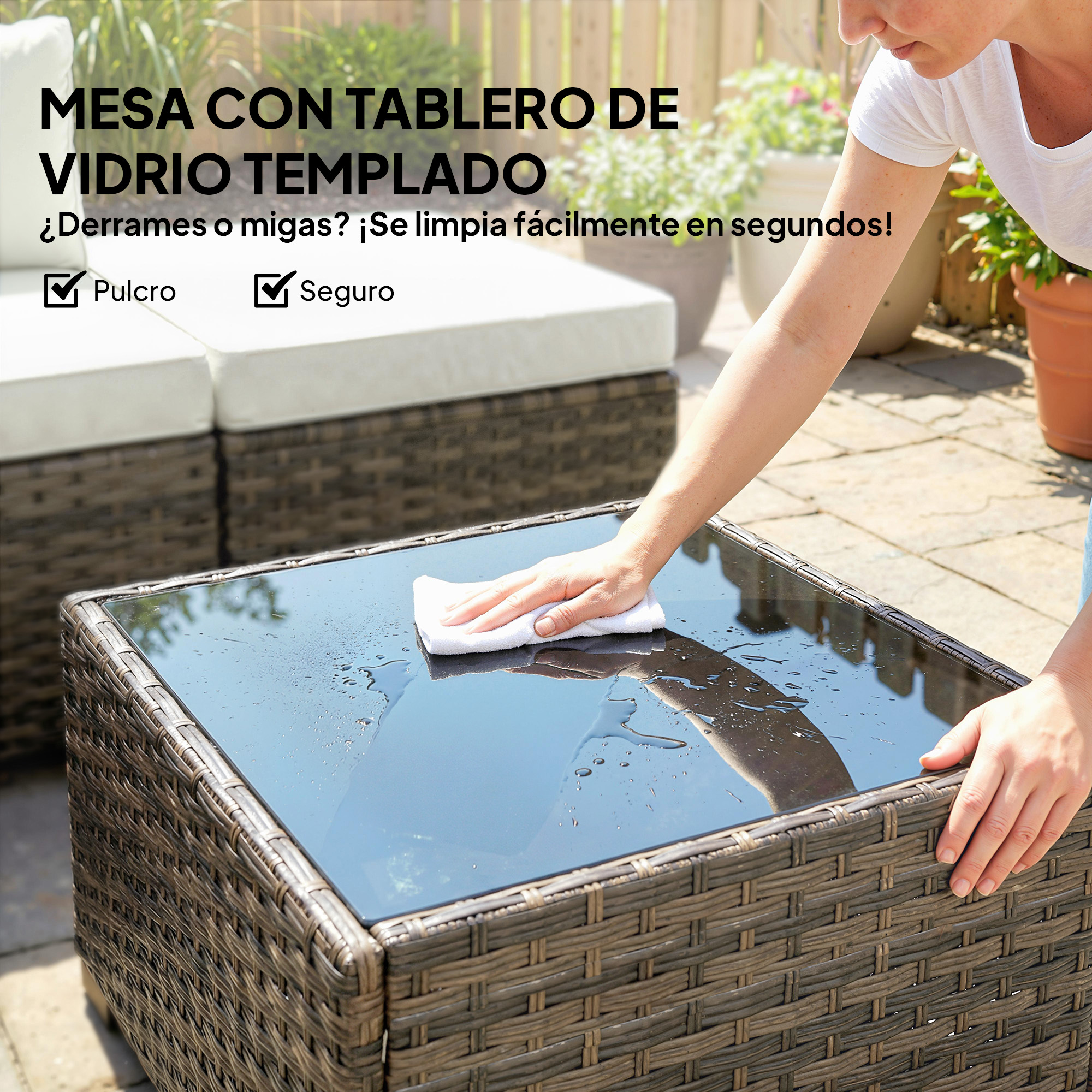 Una mano limpia una mesa de vidrio mojada sobre una base de ratán con un paño blanco.