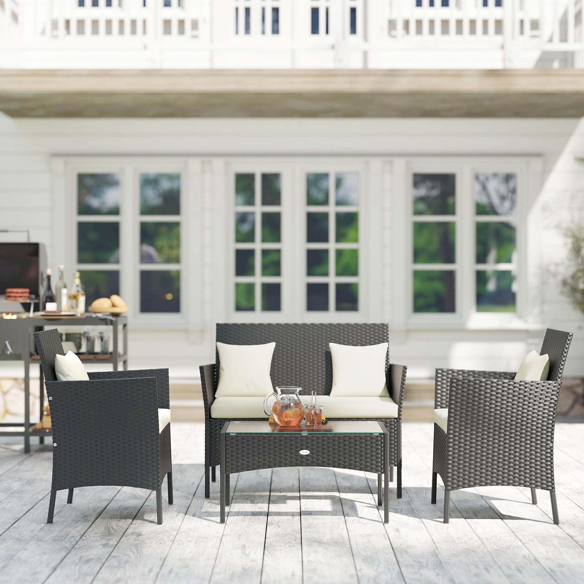 Conjunto de patio de ratán gris oscuro con cojines blancos sobre una terraza de madera.