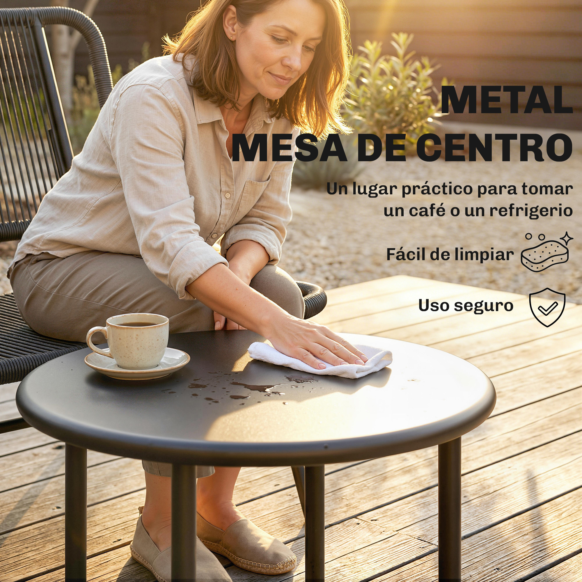 Una mujer limpia una mesa redonda de metal al aire libre con un paño.